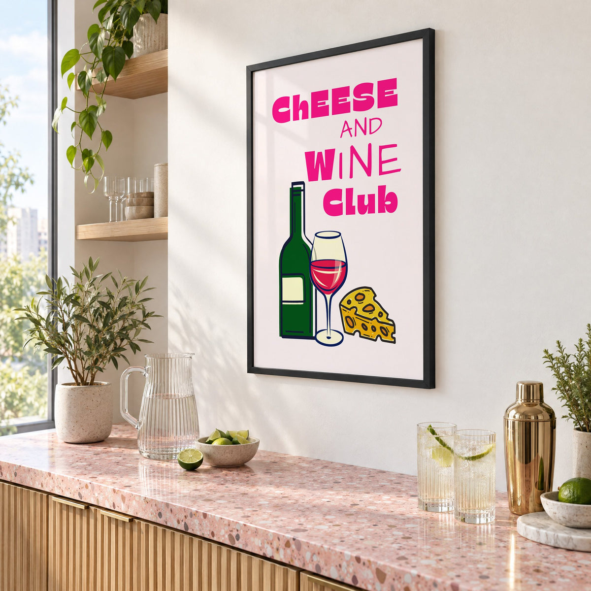 Cheese and Wine Club bottle print in a black frame above a pink terrazzo cocktail counter with limes, seen at an angle