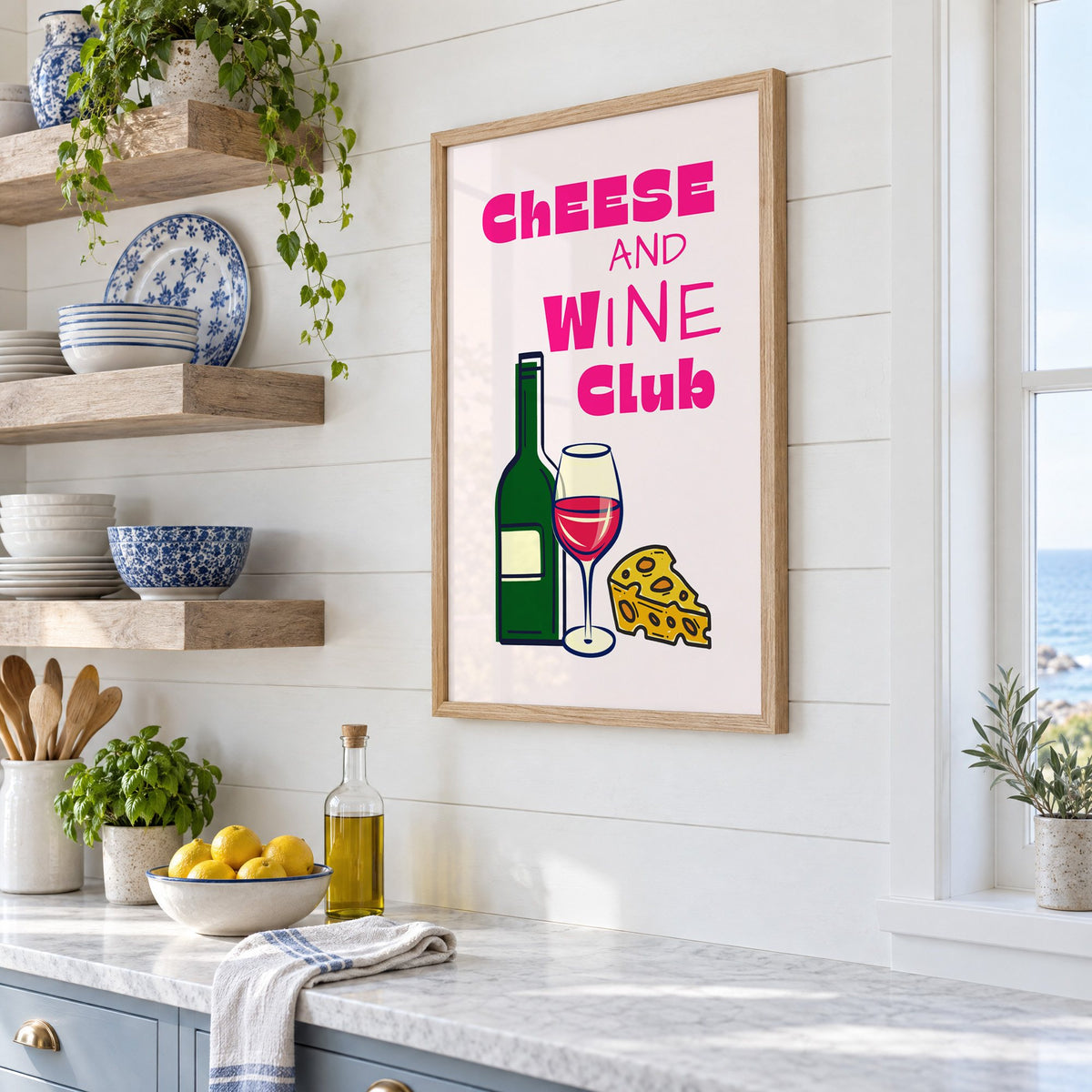 Cheese and Wine Club bottle print in an oak frame in a white coastal kitchen beside blue and white plates