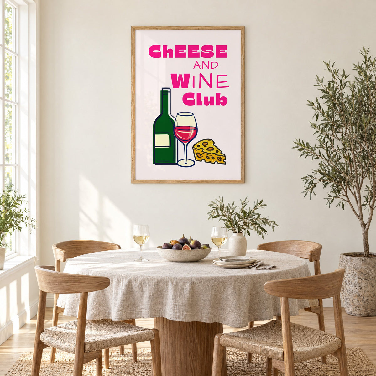 Cheese and Wine Club bottle print in an oak frame above a round linen-covered dining table with figs and wine