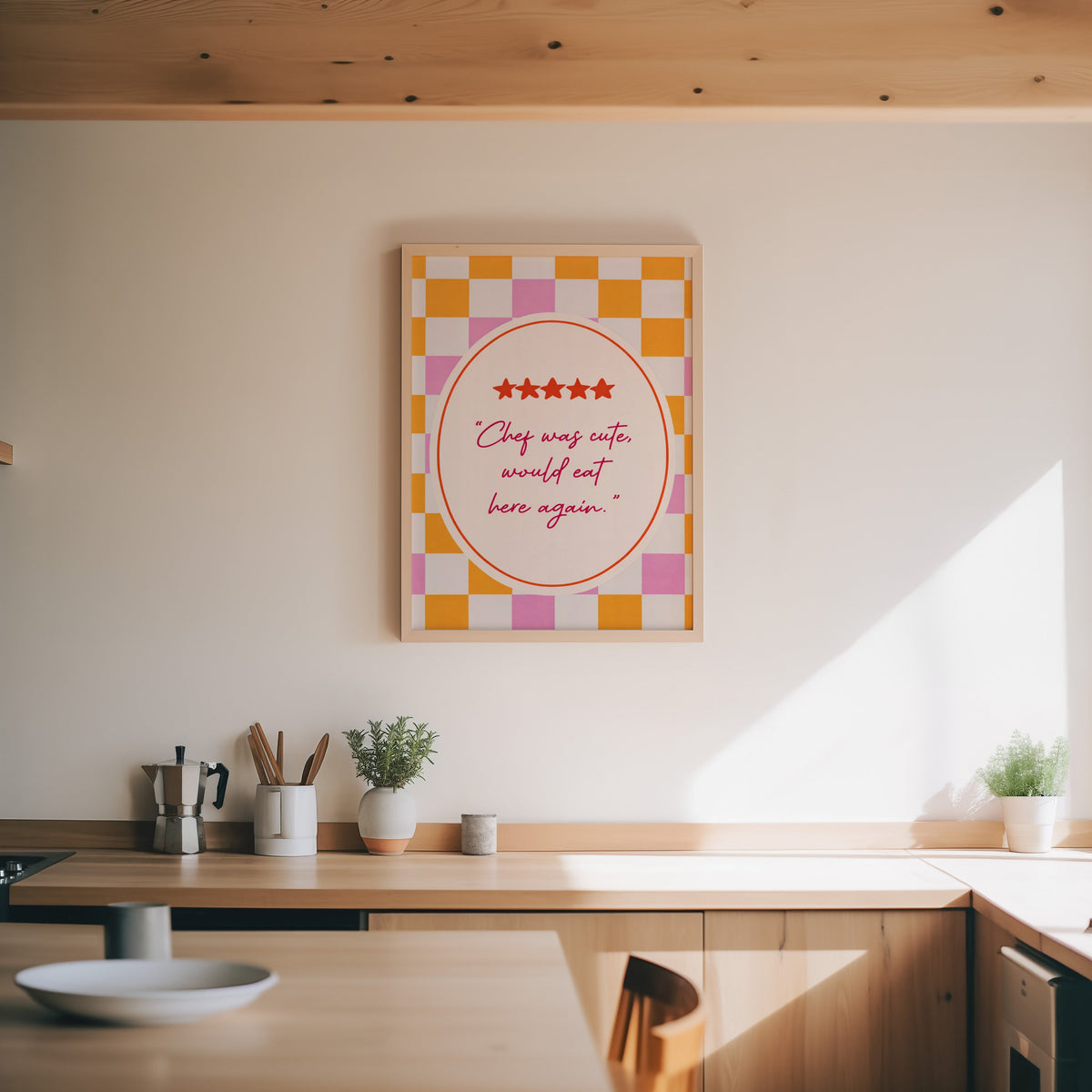 Chef Was Cute print in an oak frame above a wood counter with a moka pot and herbs