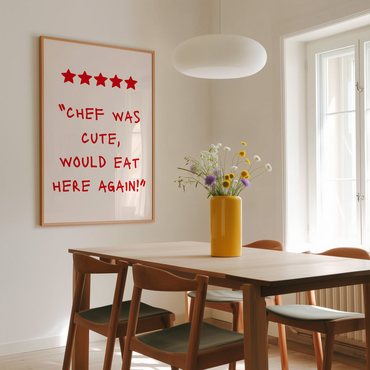 Chef Was Cute five star review print in a slim oak frame above a wooden dining table under a round pendant light