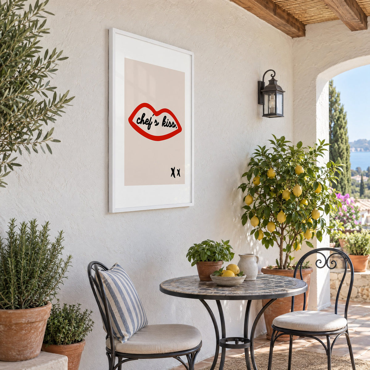 Chef's kiss red lips outline print in a white frame on a sunny patio wall beside a potted lemon tree