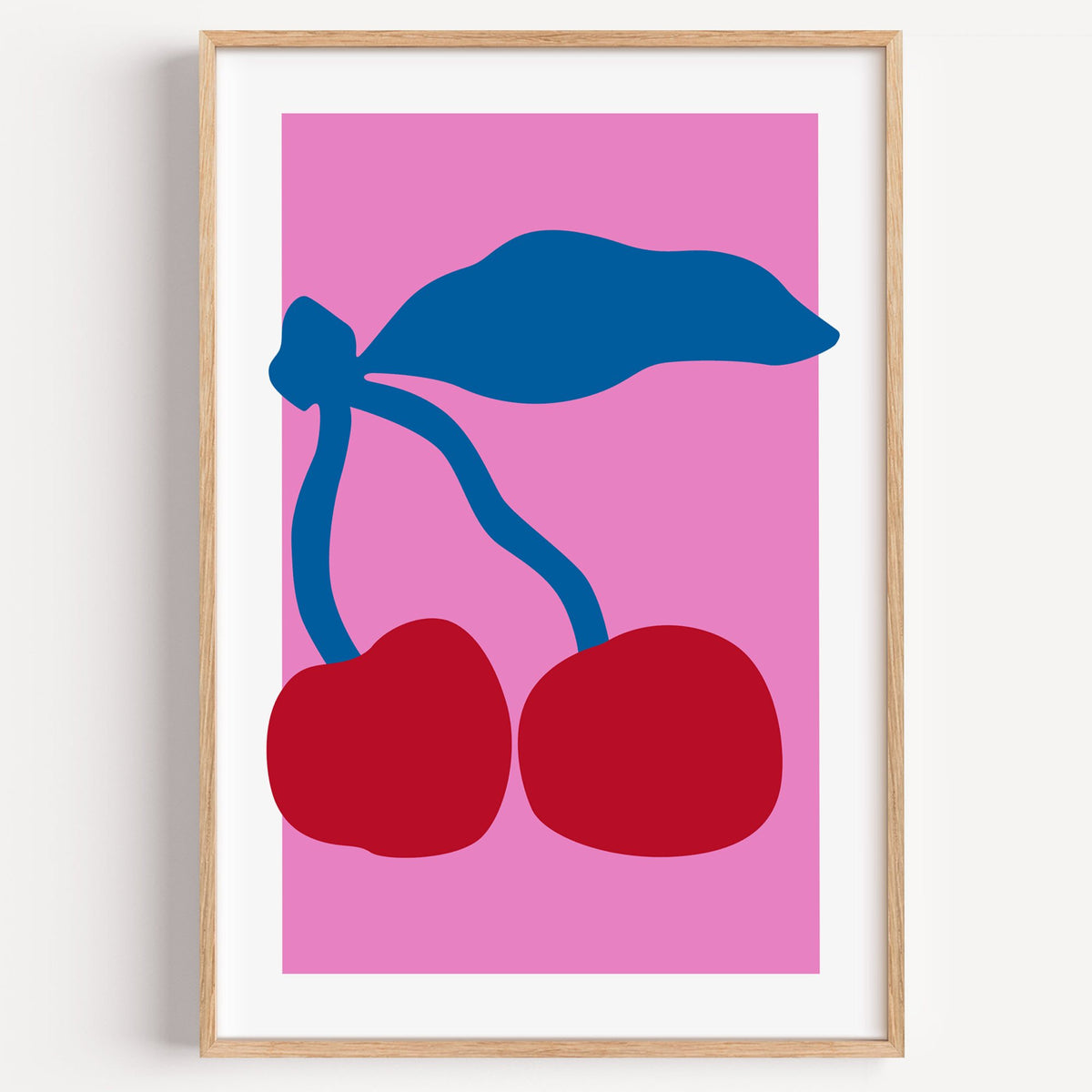 giant red cherries cobalt leaf hot pink print in a light oak frame on a plain white wall