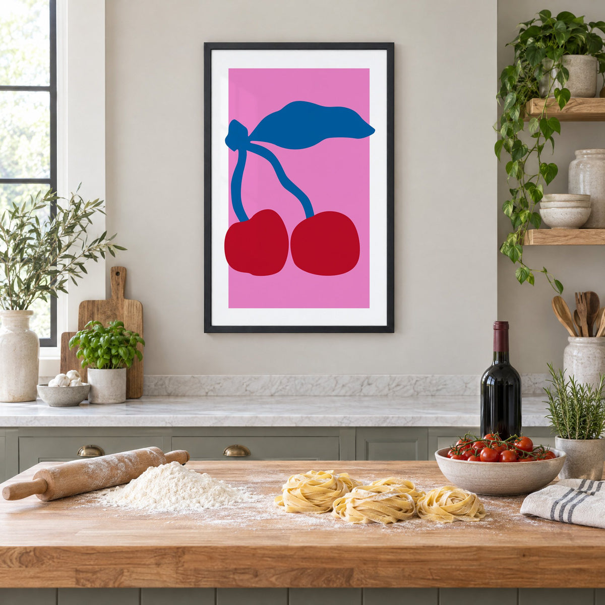 giant red cherries cobalt leaf hot pink print in a black frame above a butcher-block island with fresh pasta, flour and cherry tomatoes