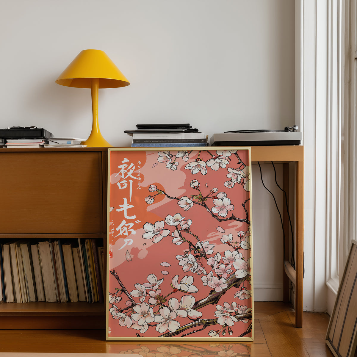 Cherry blossom branch on coral print shown in a gold frame below a teak desk with a yellow lamp
