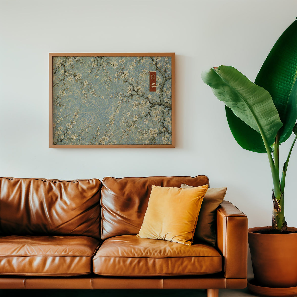 Cherry blossoms on a blue swirl sky print in a warm oak frame above a cognac leather sofa with a mustard pillow