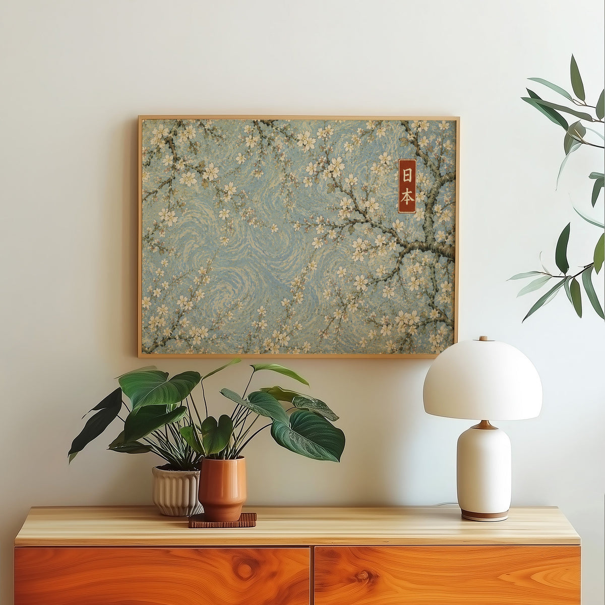 Cherry blossoms on a blue swirl sky print in a light oak frame above a wood sideboard with a white dome lamp