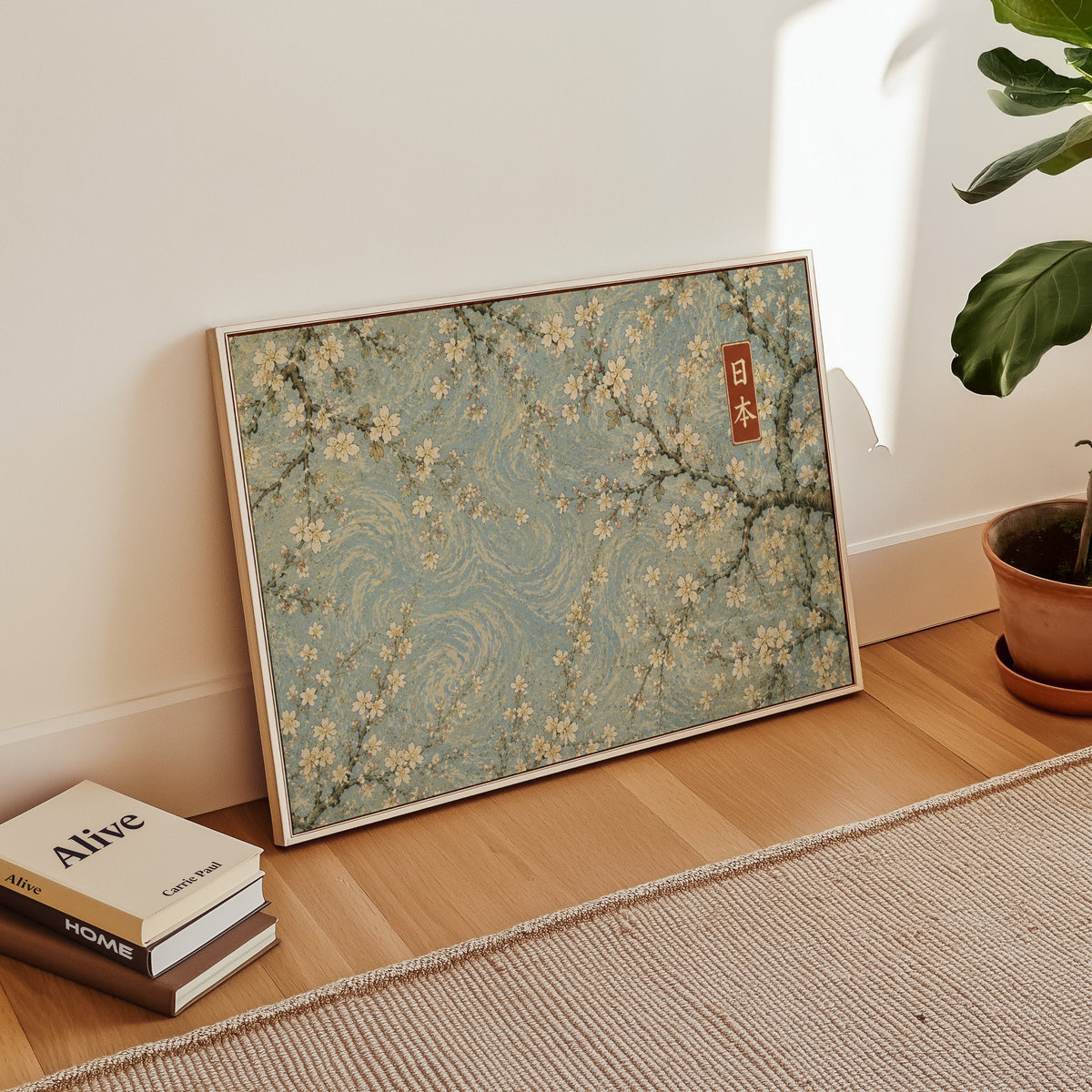 Cherry blossoms on a blue swirl sky print in a white floater frame leaning on a wood floor beside stacked books