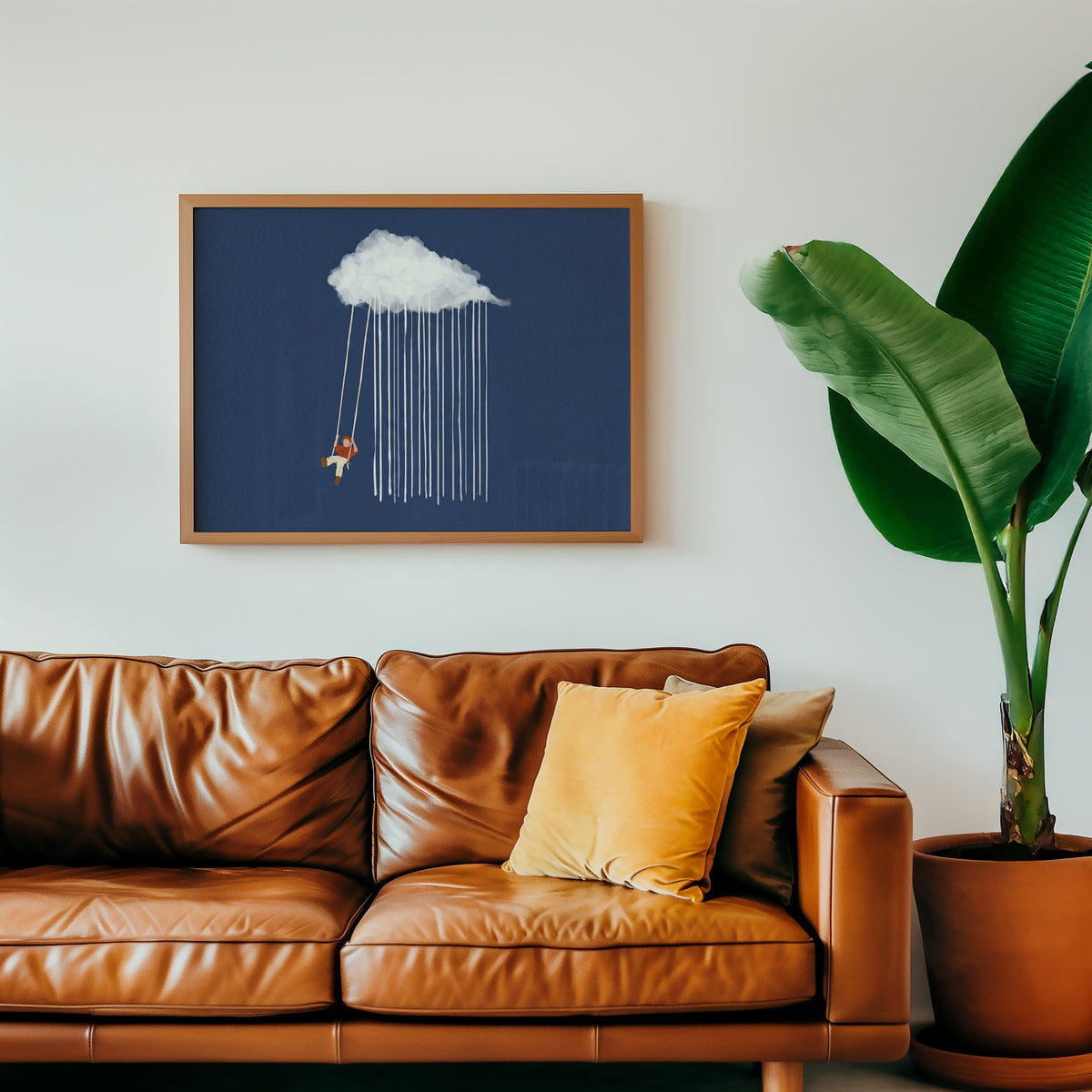 Whimsical rain cloud print in an oak frame above a cognac leather sofa