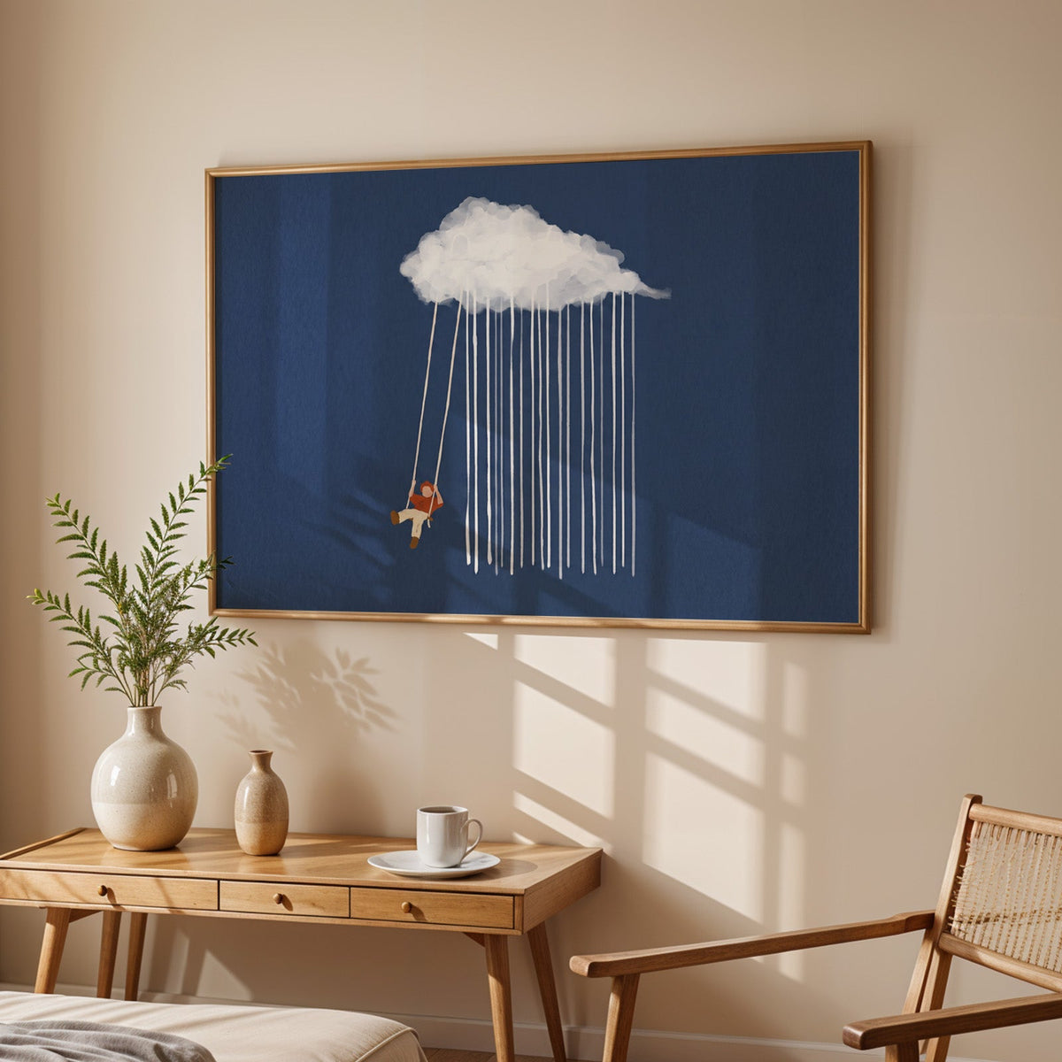 Nursery cloud swing print in an oak frame above a sunlit desk with a cane chair