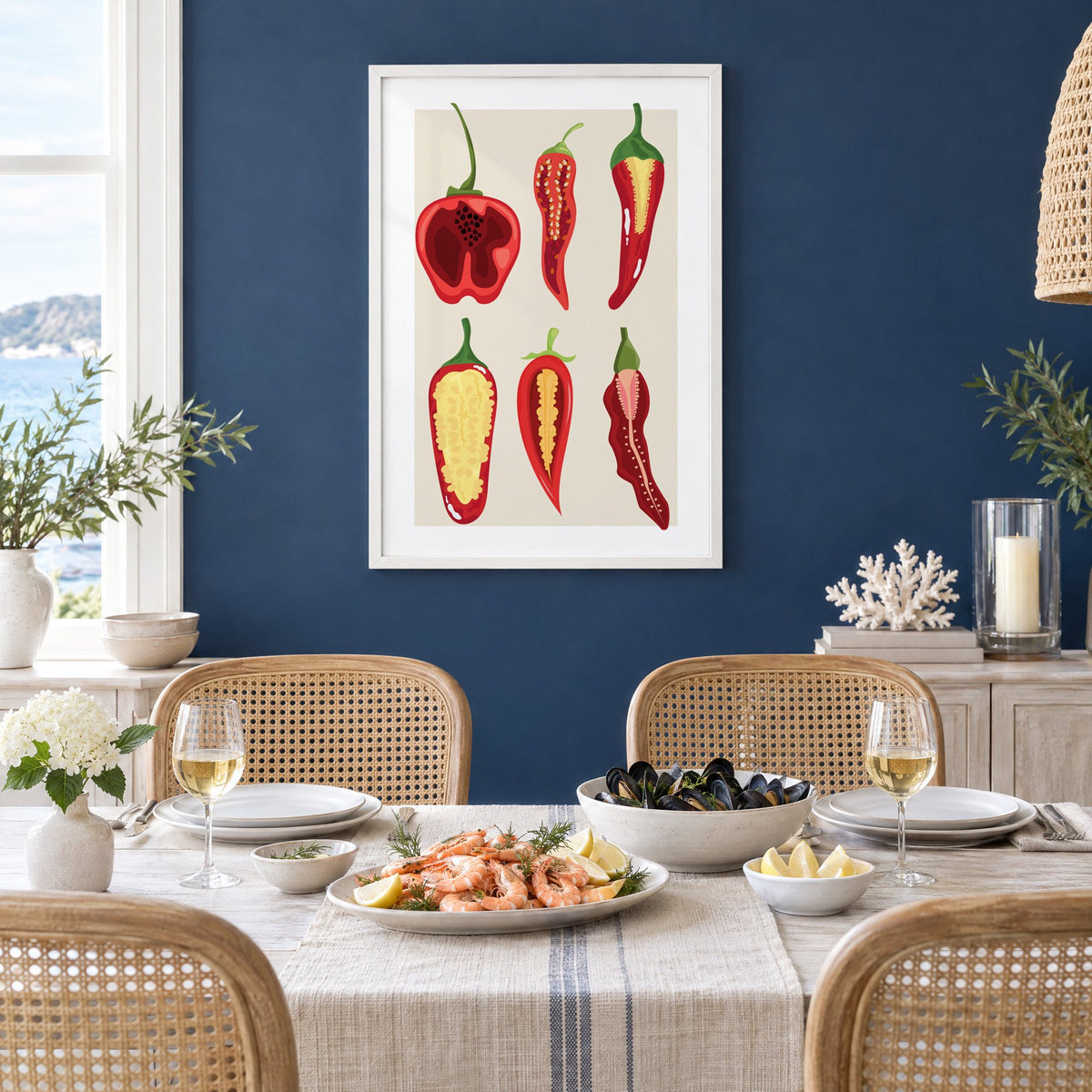 six sliced chili pepper cross sections print in a white frame on a navy wall above a dining table set with shrimp and mussels
