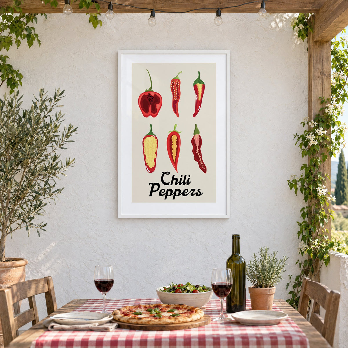Chili Peppers six halves grid print in a white frame on a stucco wall above a checked-cloth table with pizza and red wine
