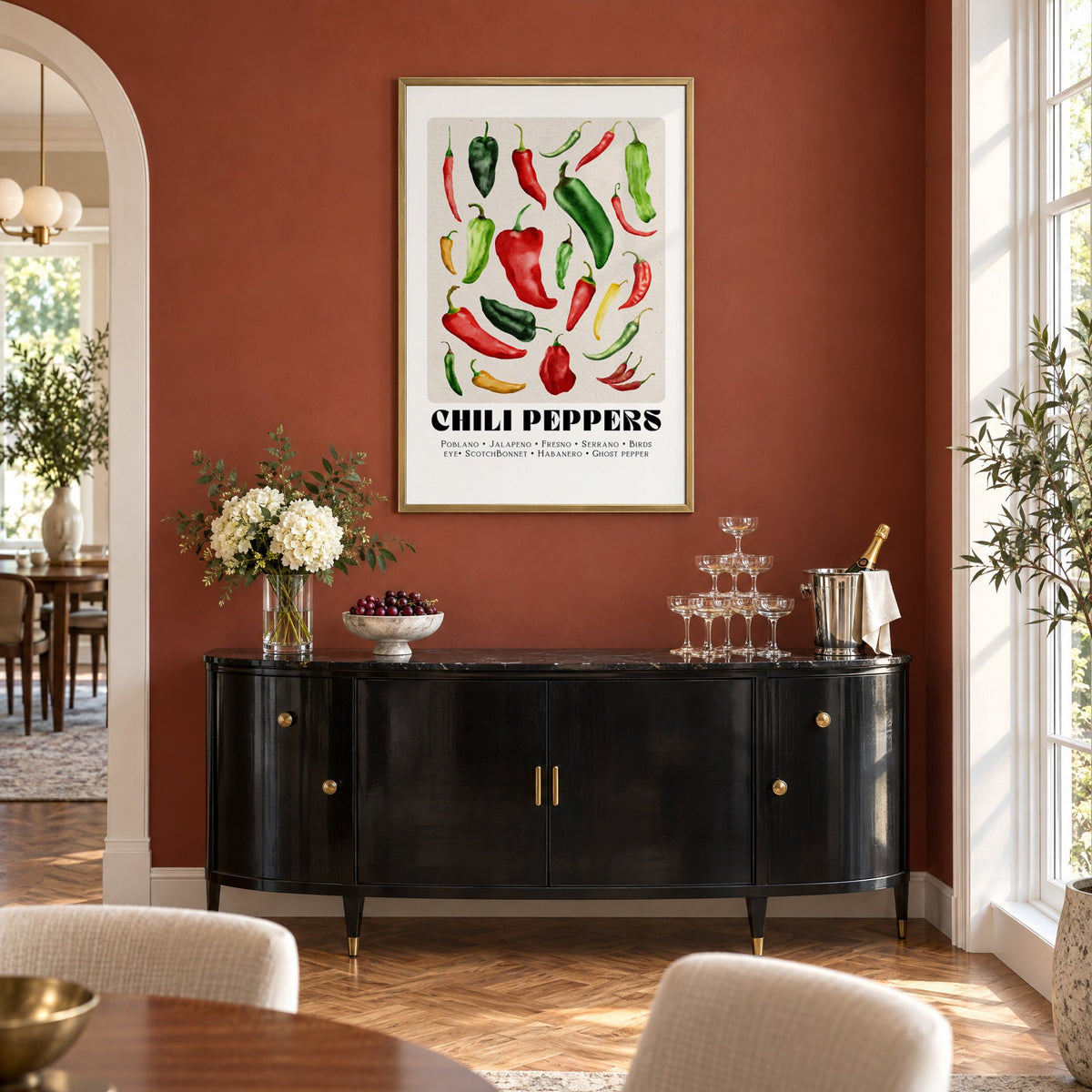 CHILI PEPPERS watercolor varieties print in a brass frame on a terracotta wall above a black buffet with a champagne tower