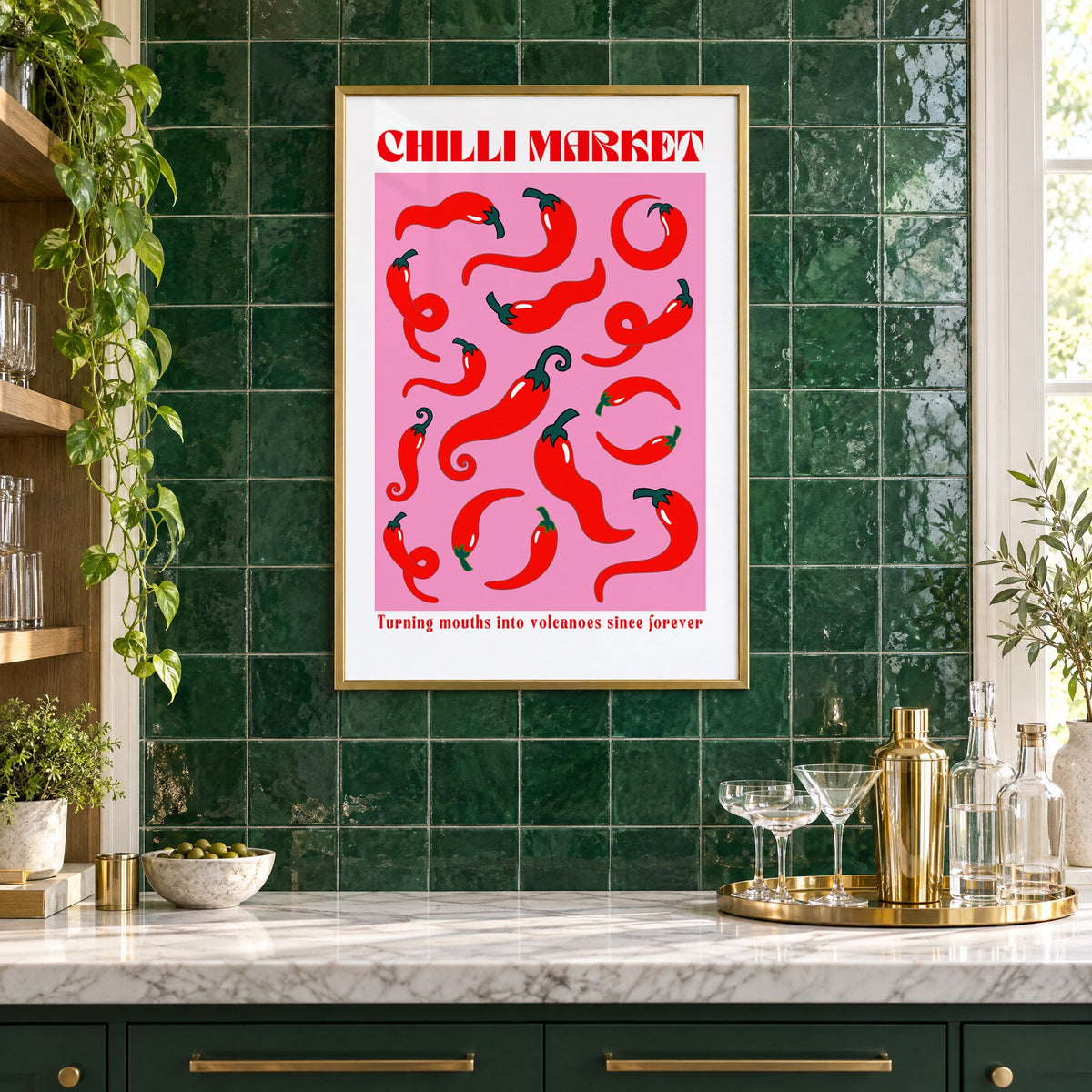 Chilli Market curly peppers print in a brass frame on emerald green tiles above a home bar with coupe glasses