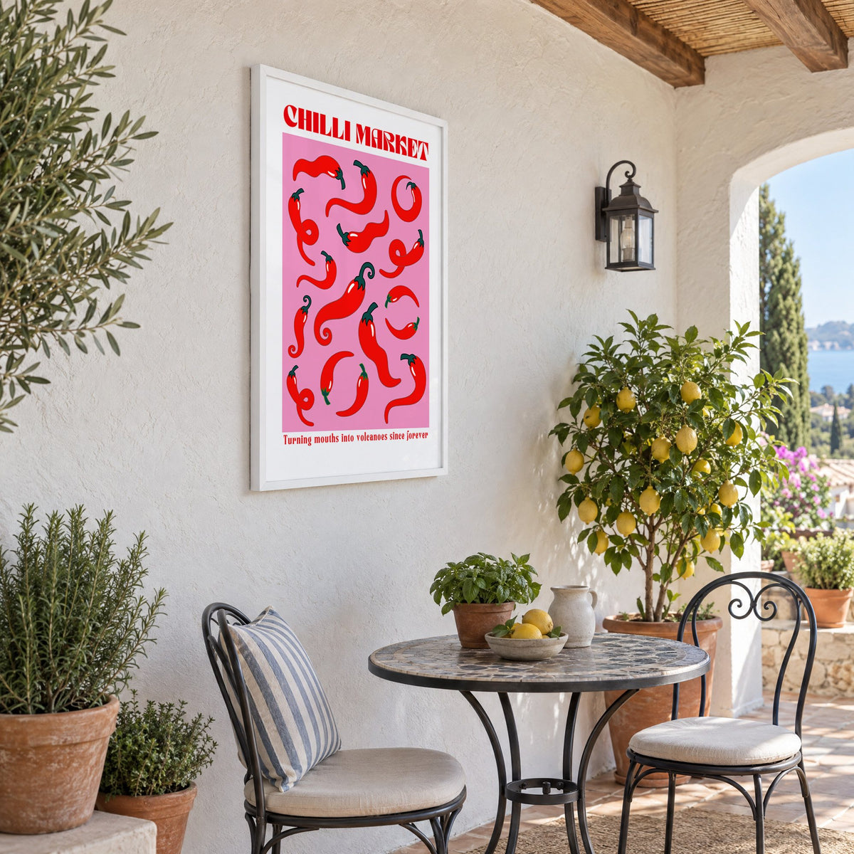 Chilli Market curly peppers print in a white frame on a sunny patio wall beside a potted lemon tree