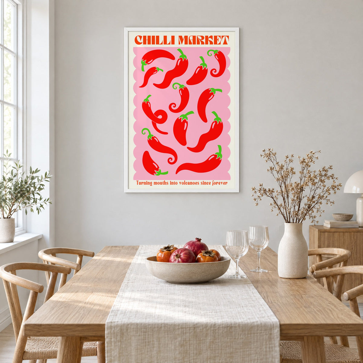 CHILLI MARKET red peppers pink scallop print in a white frame above a light oak dining table with a linen runner and fruit bowl