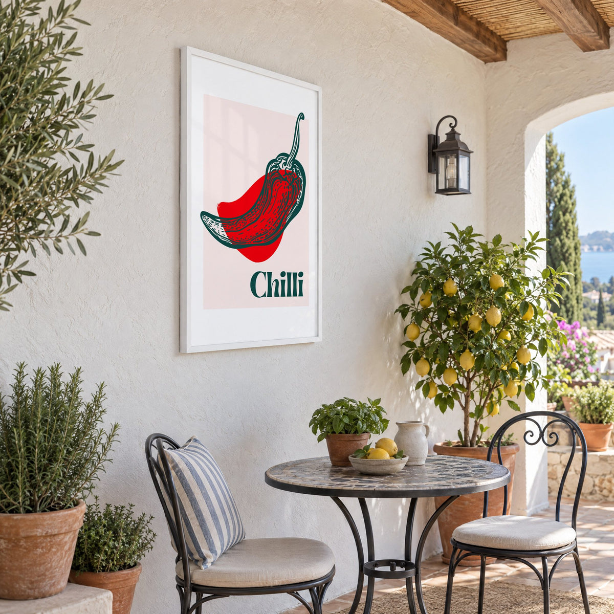 Chilli red pepper sketch print in a white frame on a sunny patio wall beside a potted lemon tree