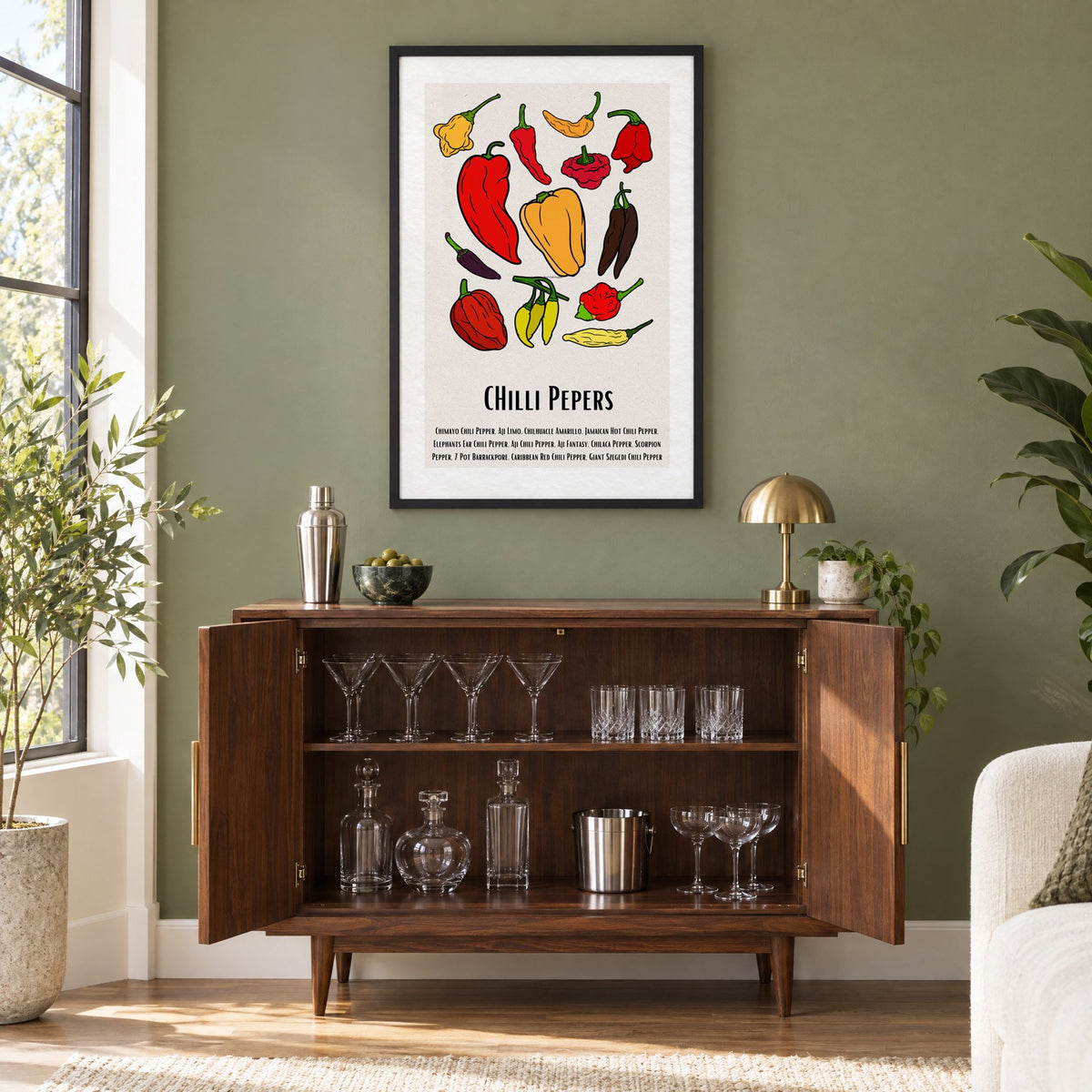 CHilli Pepers bold outline pepper chart print in a black frame on an olive green wall above a walnut bar cabinet with glassware