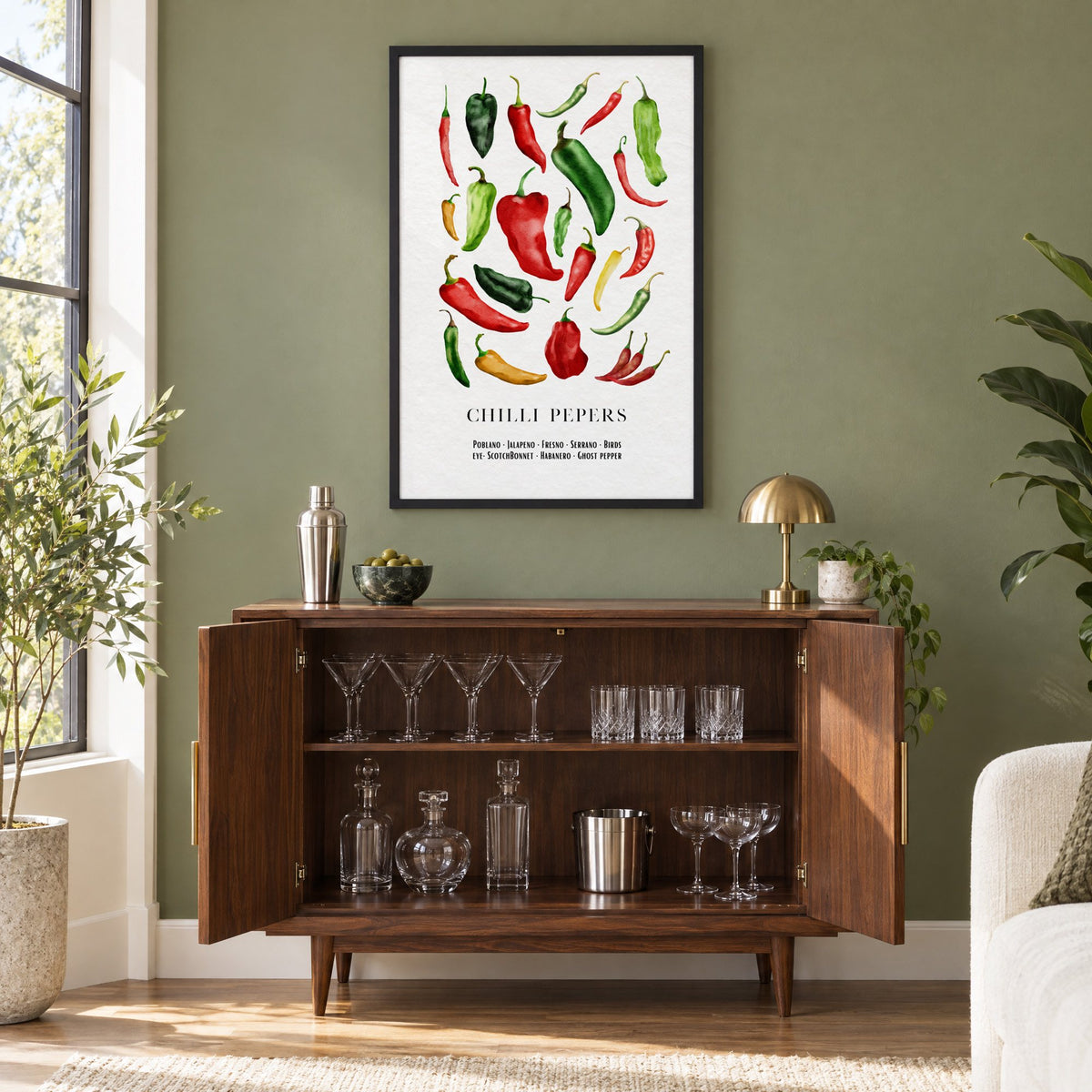 CHILLI PEPERS watercolor pepper varieties print in a black frame on an olive green wall above a walnut bar cabinet with glassware