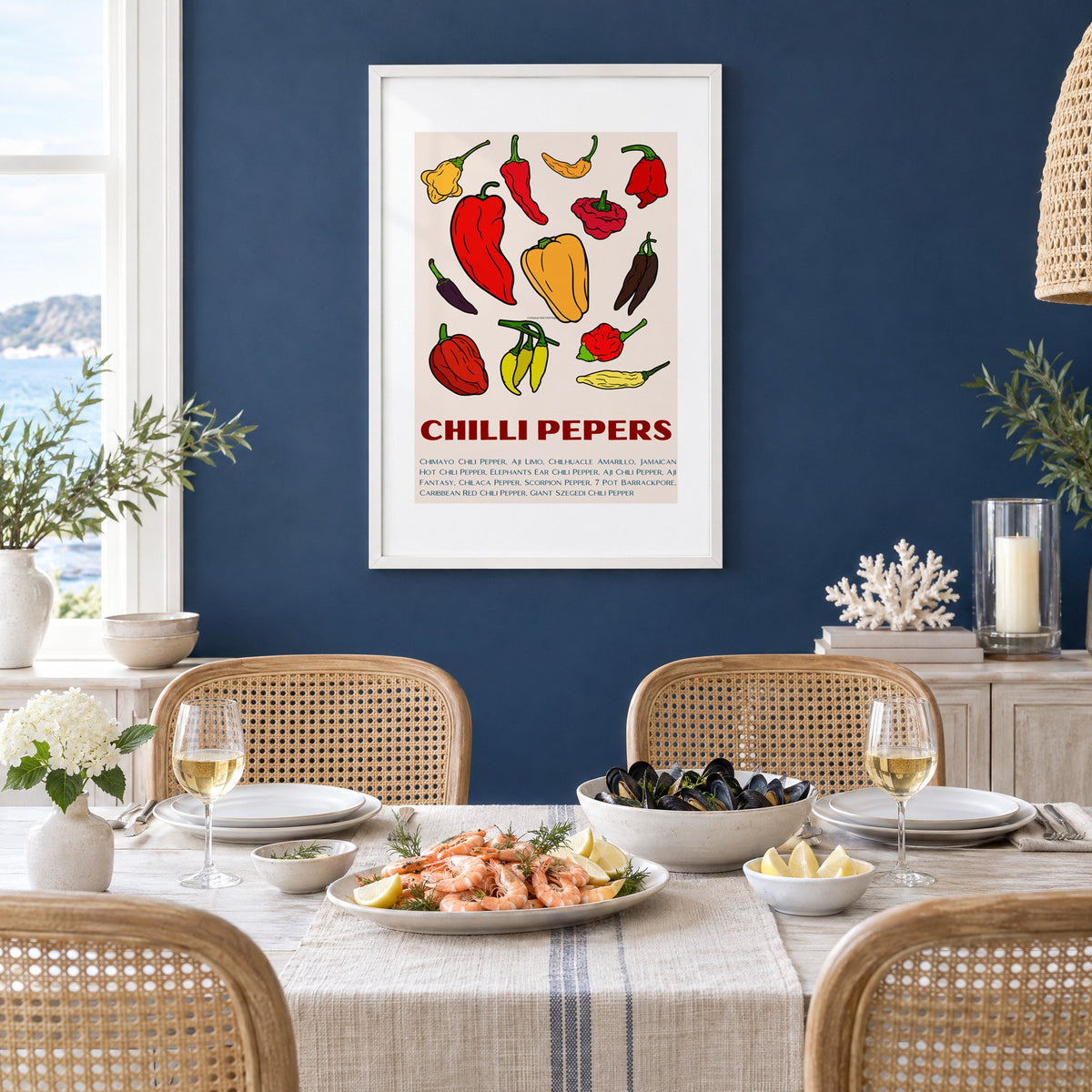 CHILLI PEPERS thirteen pepper chart print in a white frame on a navy wall above a dining table set with shrimp and mussels