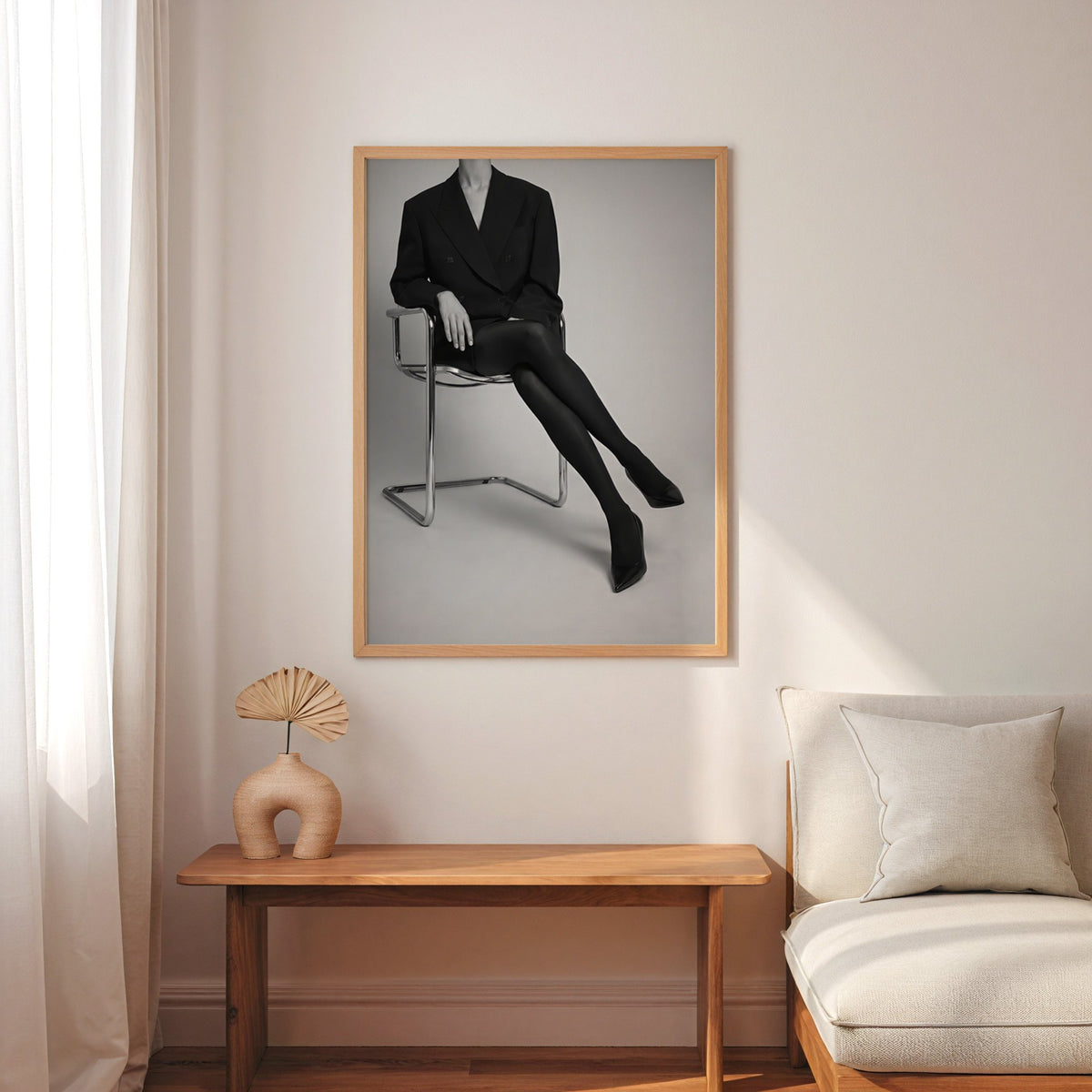 Black and white chrome chair blazer studio print in an oak frame above a narrow console with an arched vase
