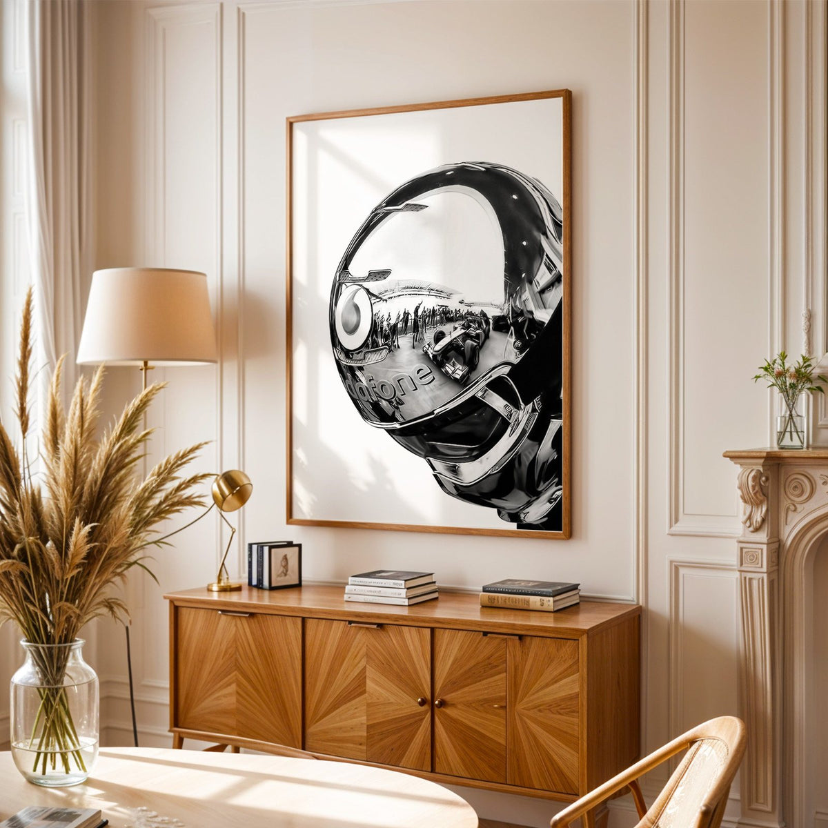 Chrome racing helmet with reflected race cars print in an oak frame above a sunburst wood sideboard with pampas grass