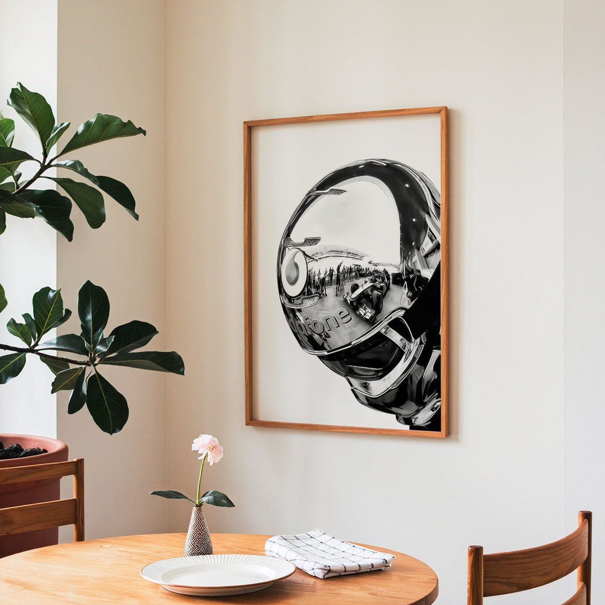 Chrome racing helmet with reflected race cars print in a teak frame above a round wooden dining table