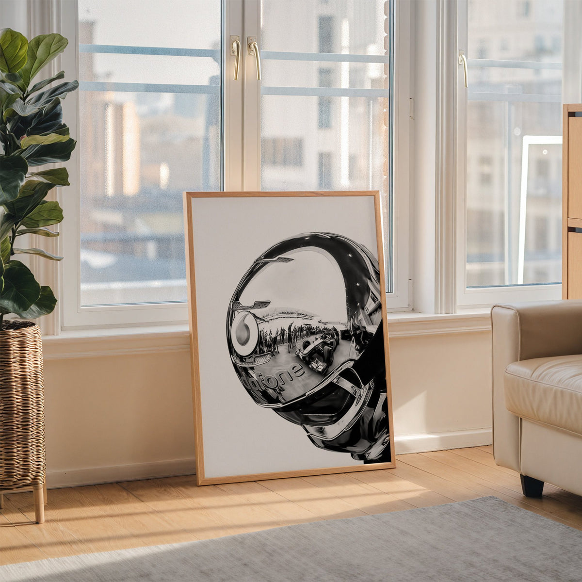 Chrome racing helmet with reflected race cars print in an oak frame leaning on the floor beside a fiddle leaf fig