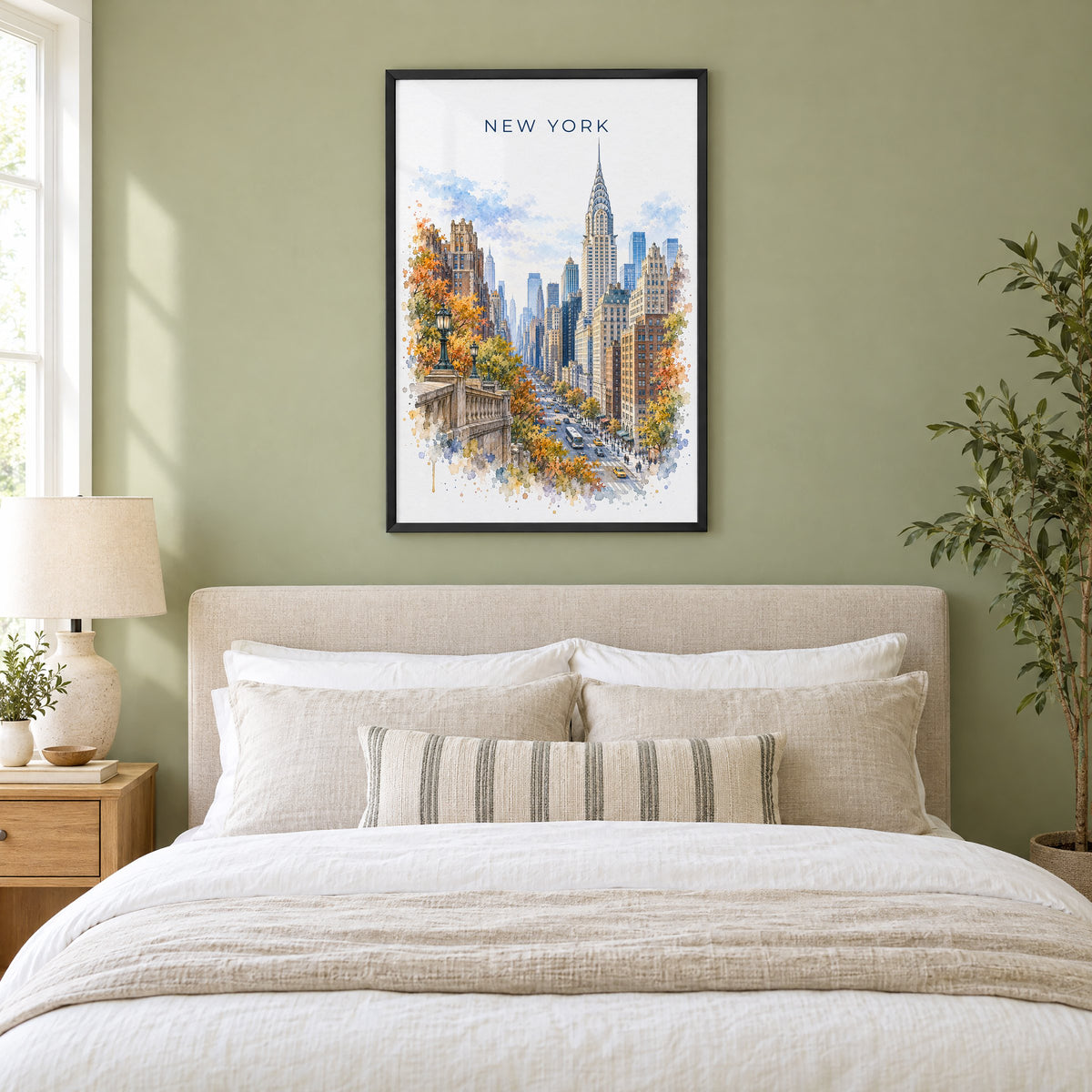Chrysler Building watercolor print in a black frame above an upholstered headboard in a sage green bedroom