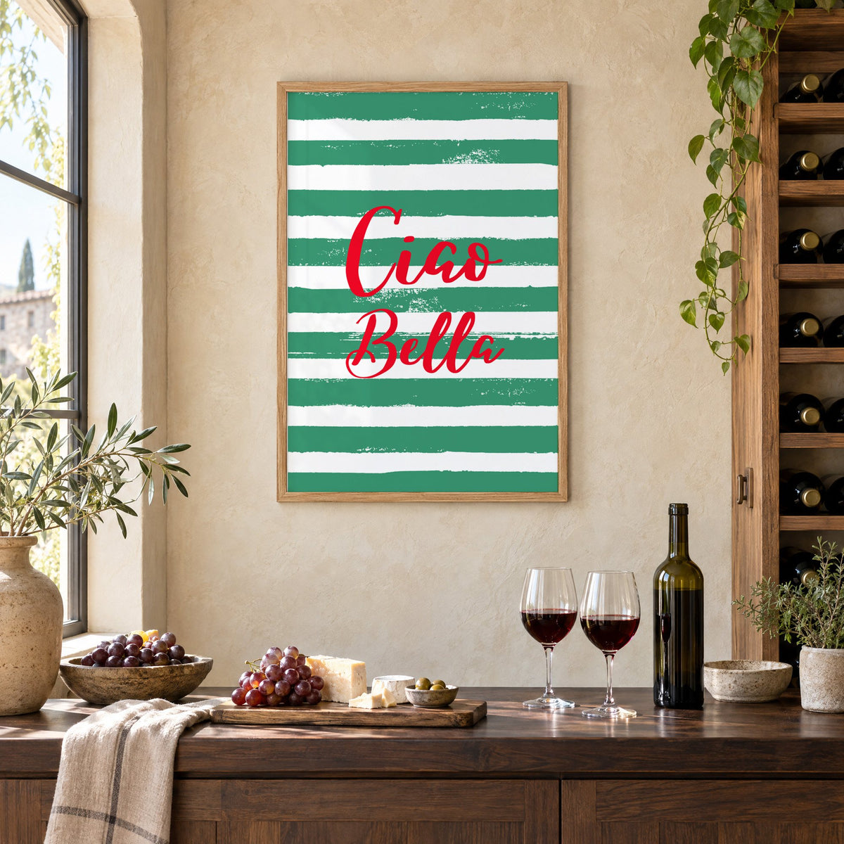 Ciao Bella red script on green stripes print in an oak frame on a limewashed wall above a wine counter with red wine, cheese and grapes