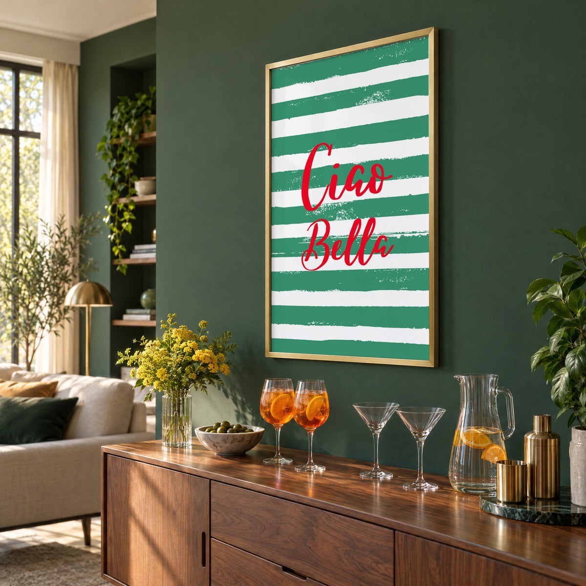 Ciao Bella red script on green stripes print in a brass frame on a bottle green wall above a sideboard with spritz and martini glasses, seen at an angle
