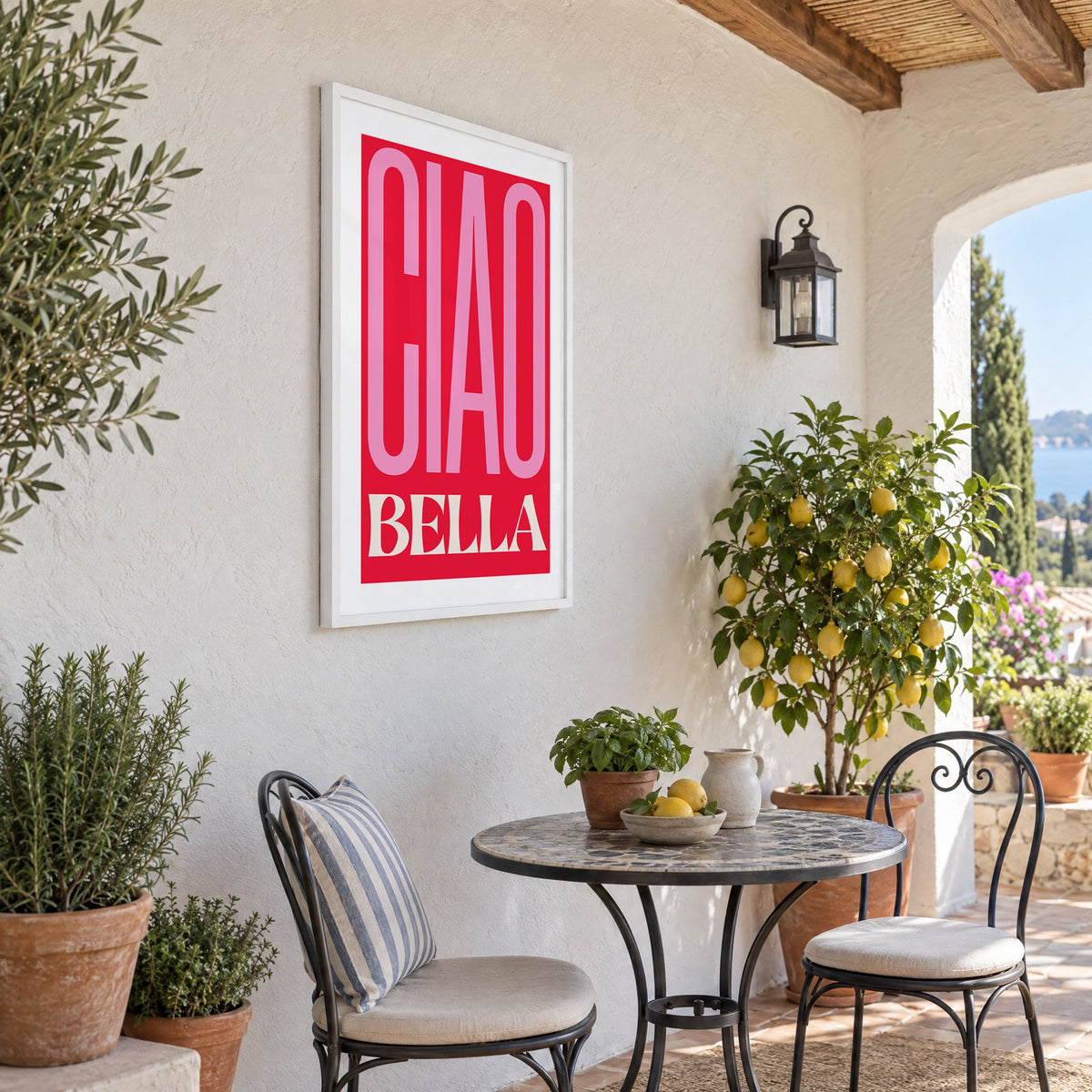 Ciao Bella pink and red type print in a white frame on a sunny patio wall beside a potted lemon tree