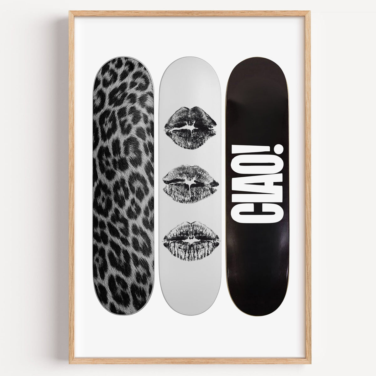 Three skateboards with fur and black lip marks print in a light oak frame on a plain white wall