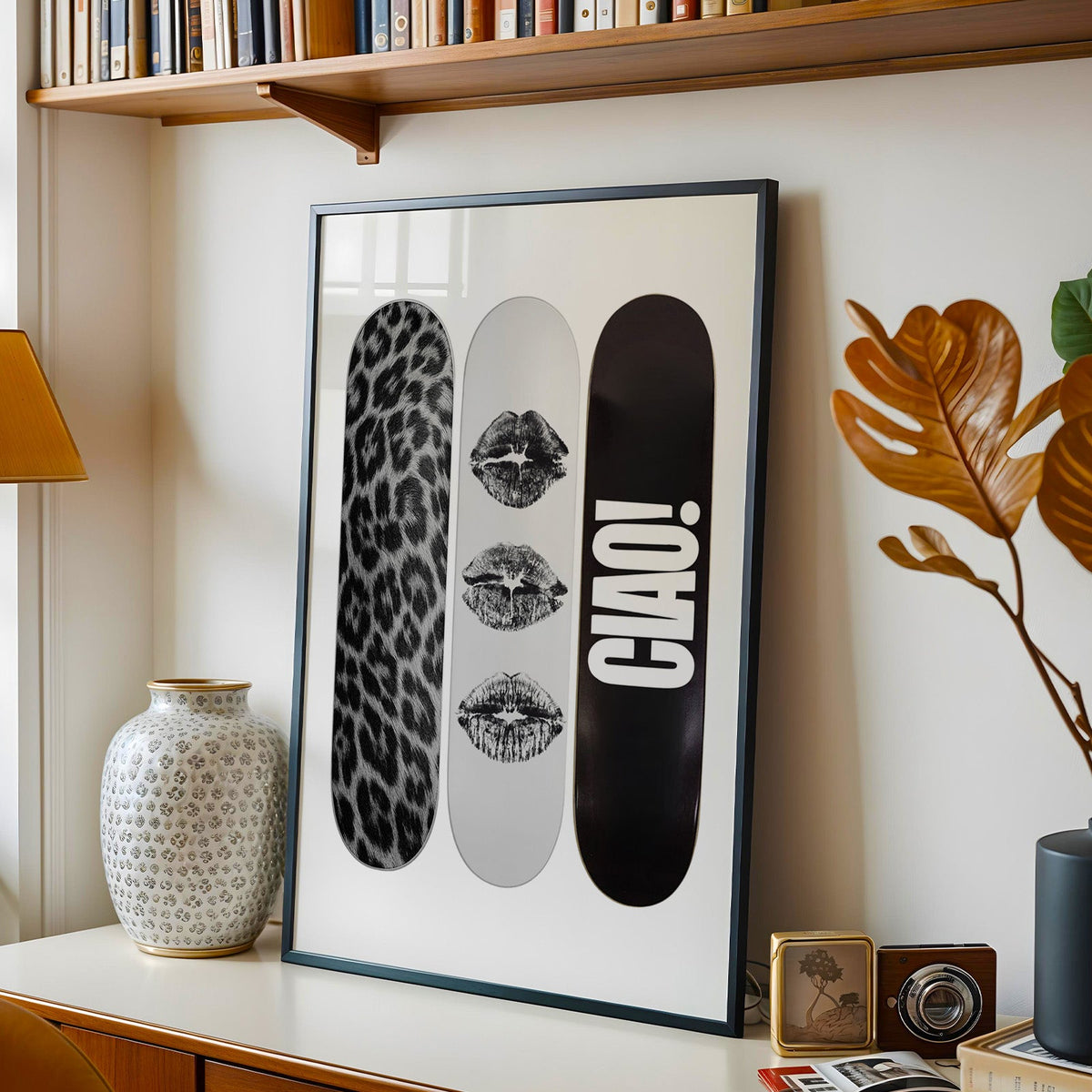 Three skateboards with fur and black lip marks print in a black frame on a console under a bookshelf