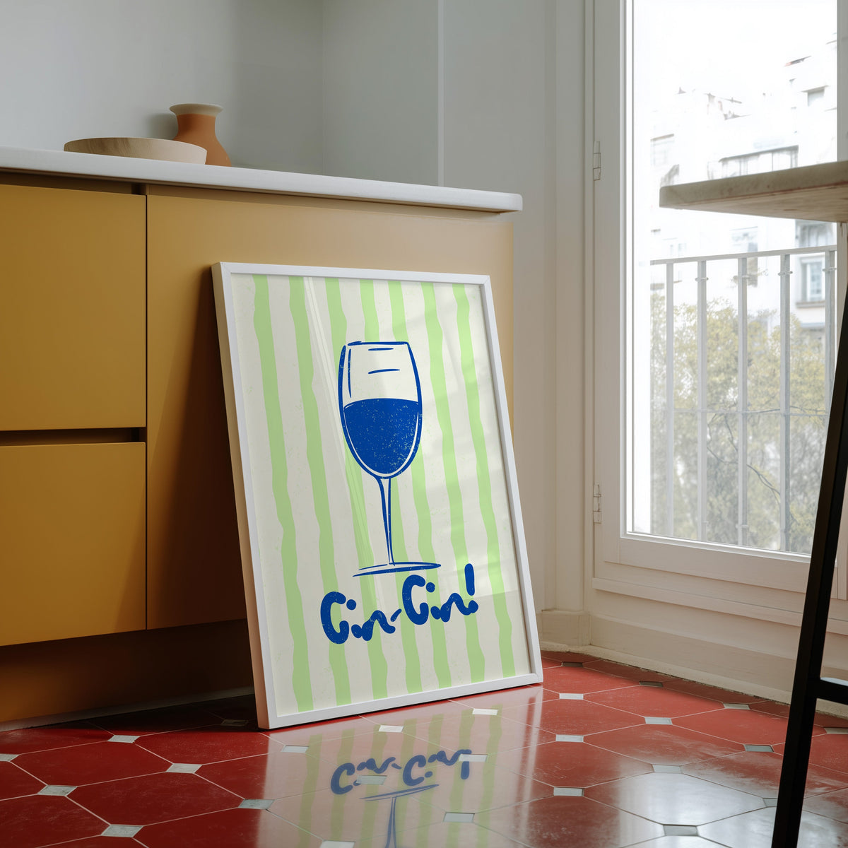 Cin Cin blue glass print in a white frame against yellow cabinets on a red tiled floor