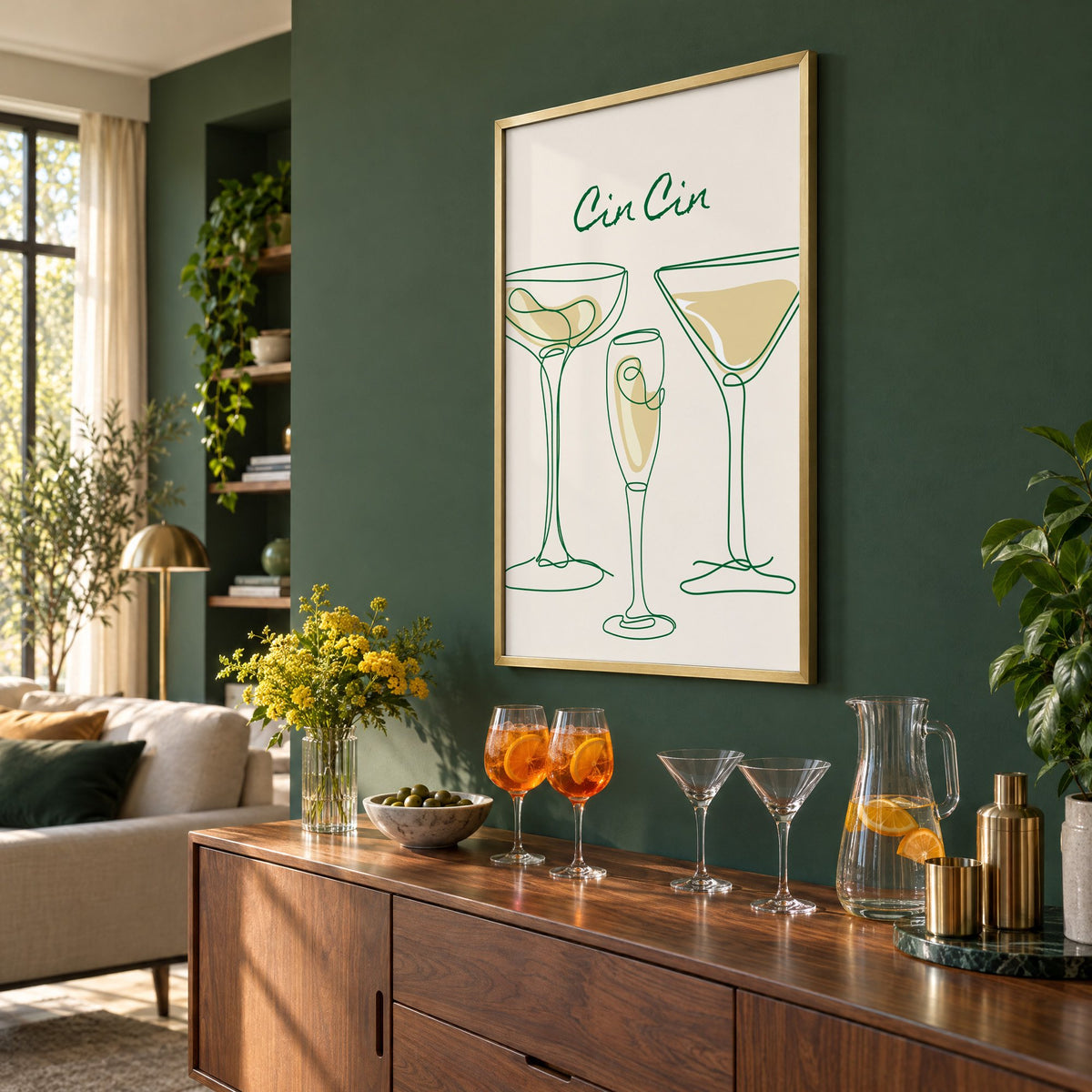 Cin Cin continuous line cocktail glasses print in a brass frame on a bottle green wall above a sideboard with spritz and martini glasses, seen at an angle