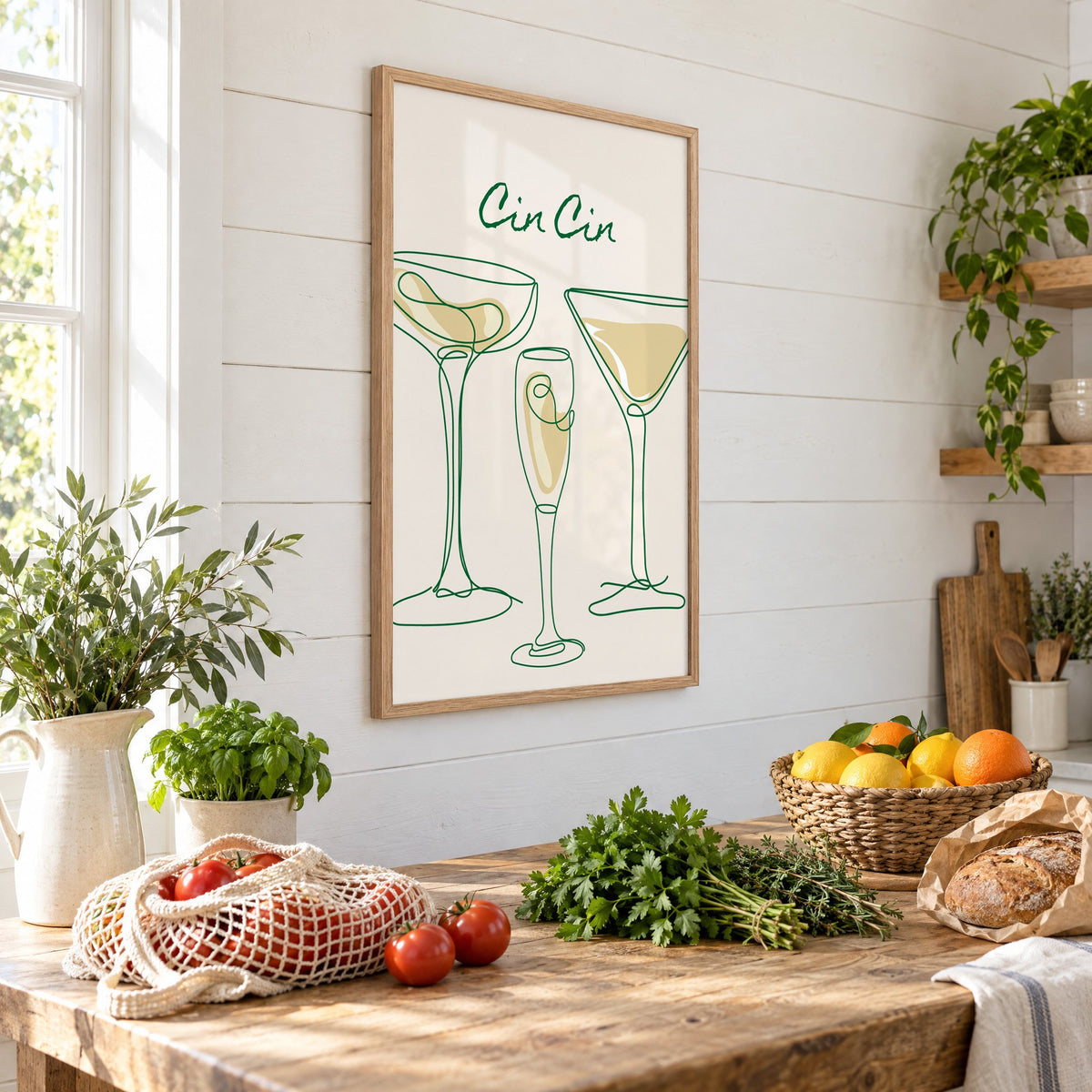 Cin Cin continuous line cocktail glasses print in an oak frame on a shiplap wall above a farm table with market tomatoes and citrus, seen at an angle