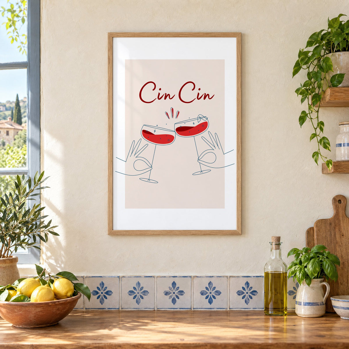 Cin Cin script two hands clinking red coupes print in an oak frame on a cream plaster wall above a worktop with a bowl of lemons and blue-and-white tiles