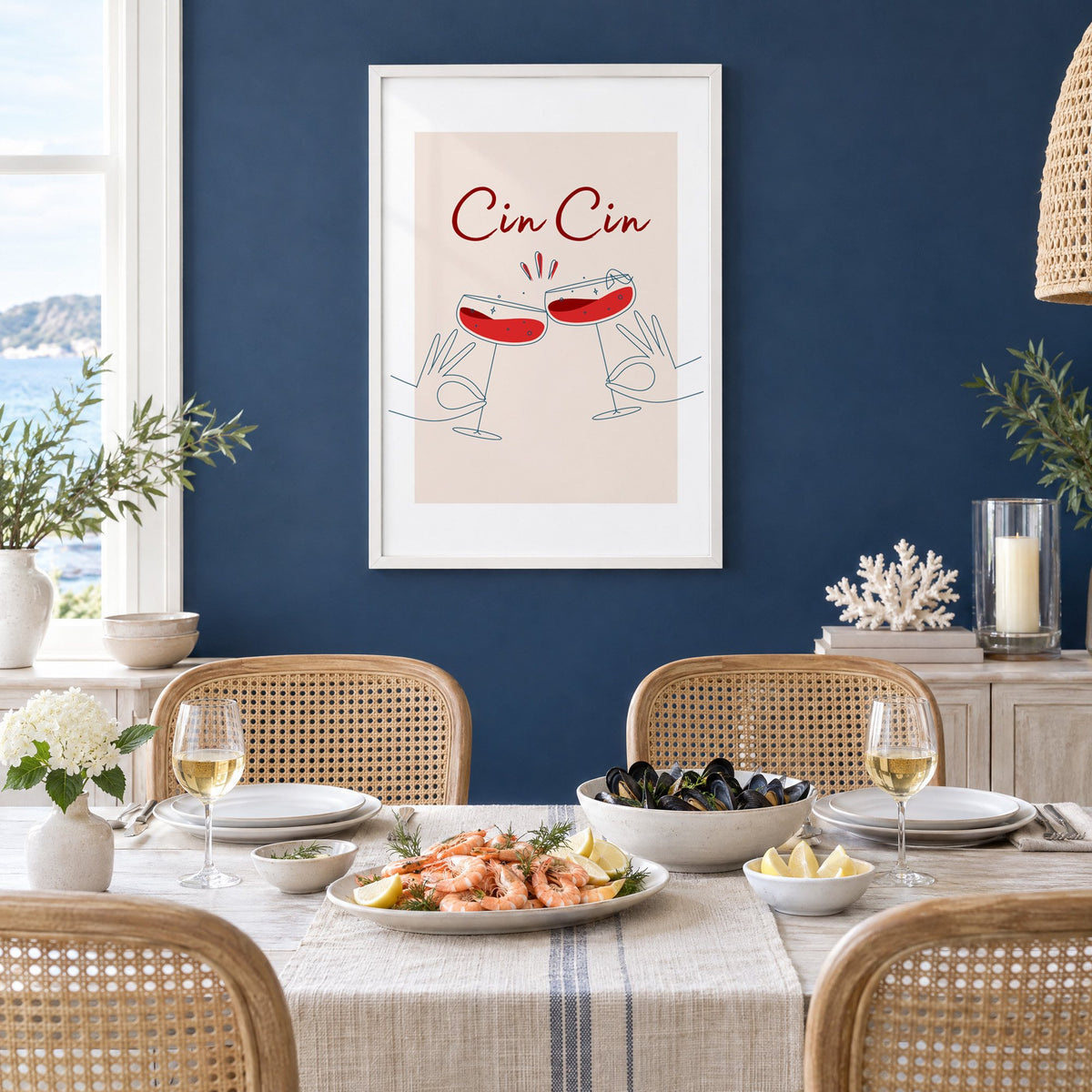 Cin Cin script two hands clinking red coupes print in a white frame on a navy wall above a dining table set with shrimp and mussels