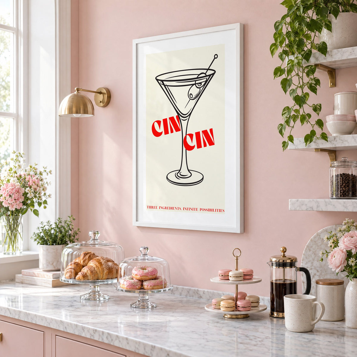 CIN CIN red type martini olives print in a white frame on a blush pink wall above a patisserie counter with croissants and macarons, seen at an angle