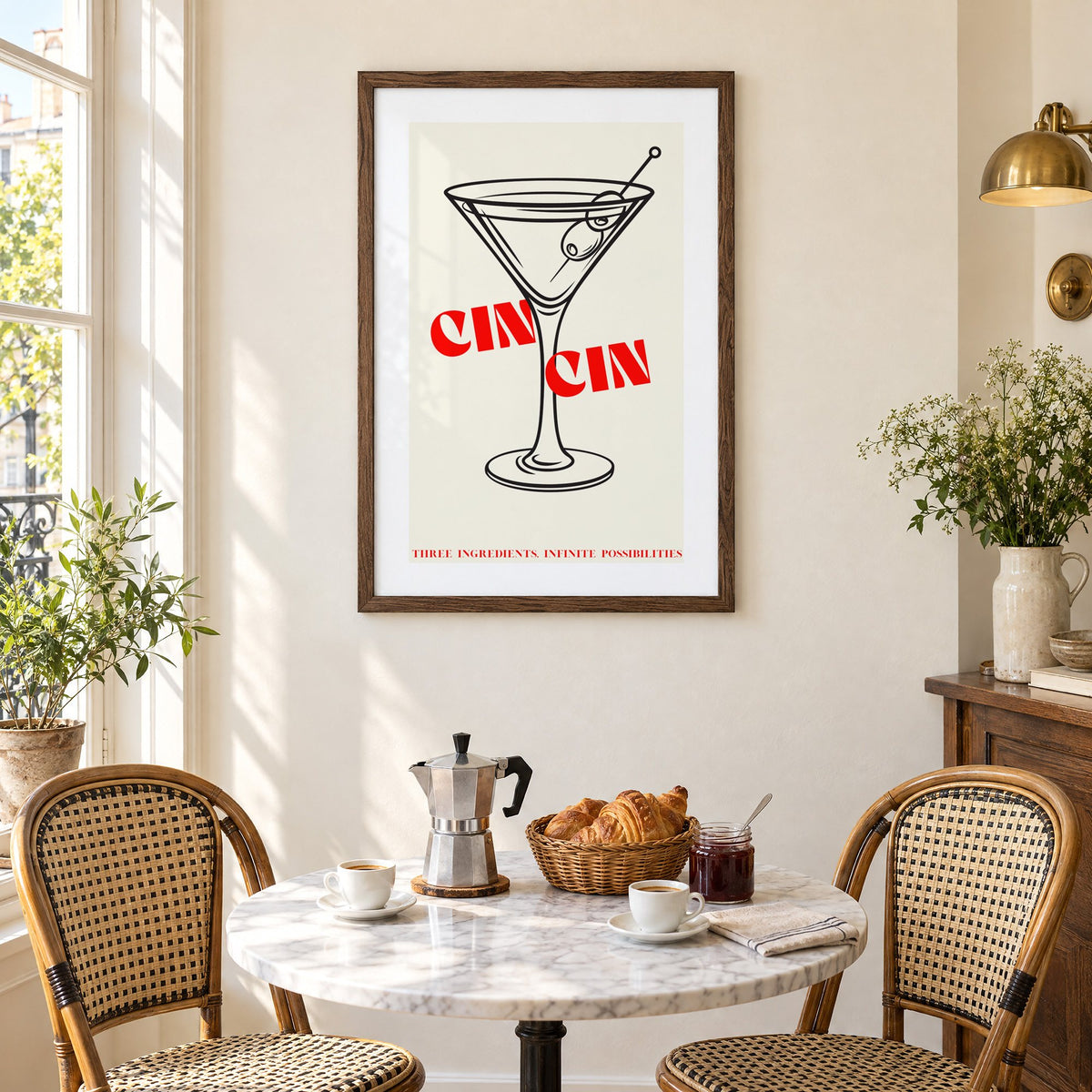 CIN CIN red type martini olives print in a walnut frame above a marble bistro table with croissants and rattan chairs