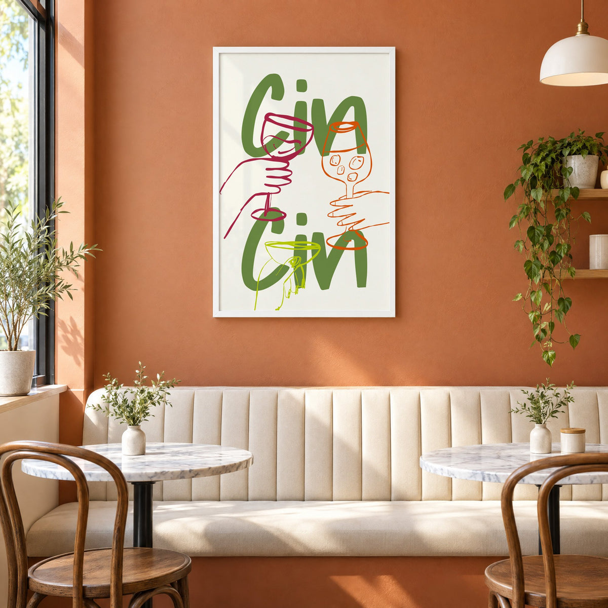 Cin Cin olive green three glasses print in a white frame above a cream banquette on a terracotta cafe wall