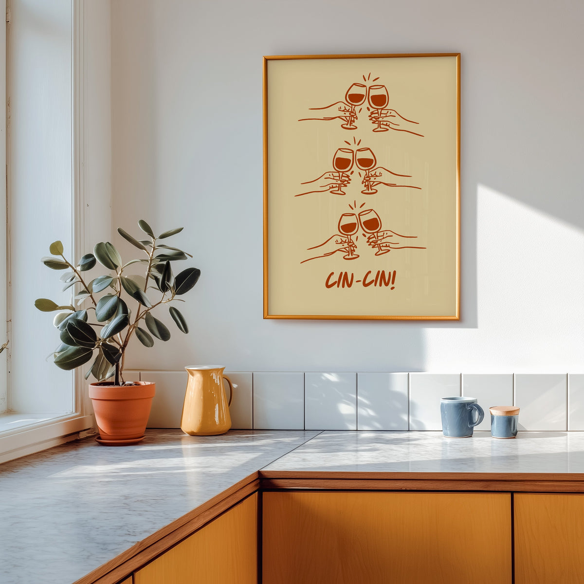 Cin Cin toasting hands print shown in a gold frame above a marble counter in a tan kitchen