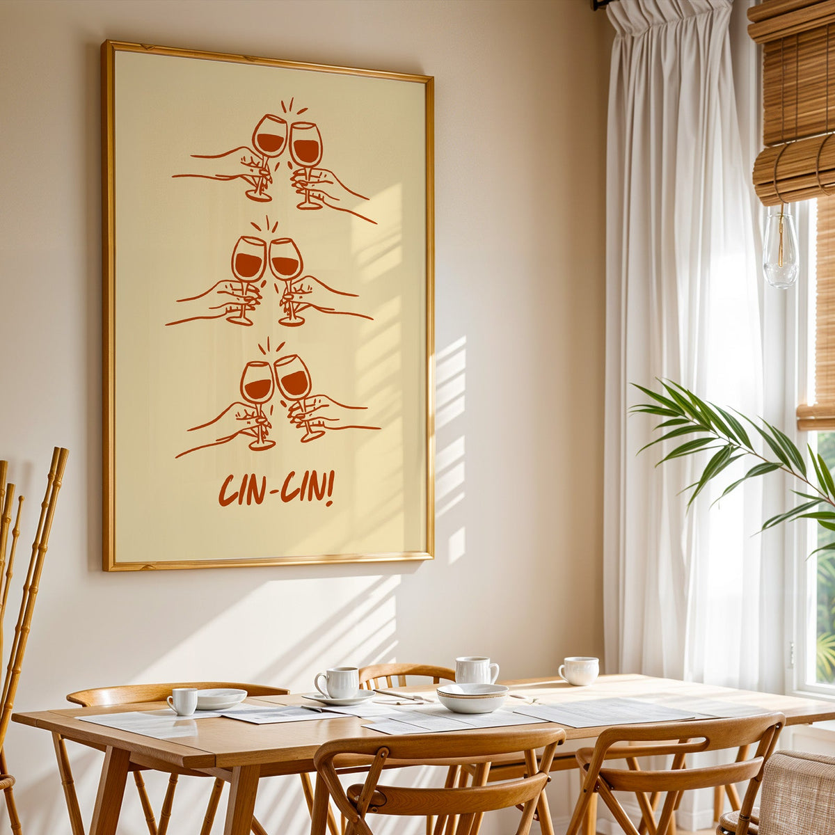 Cin Cin toasting hands print shown in a gold frame above a breakfast table by a curtained window