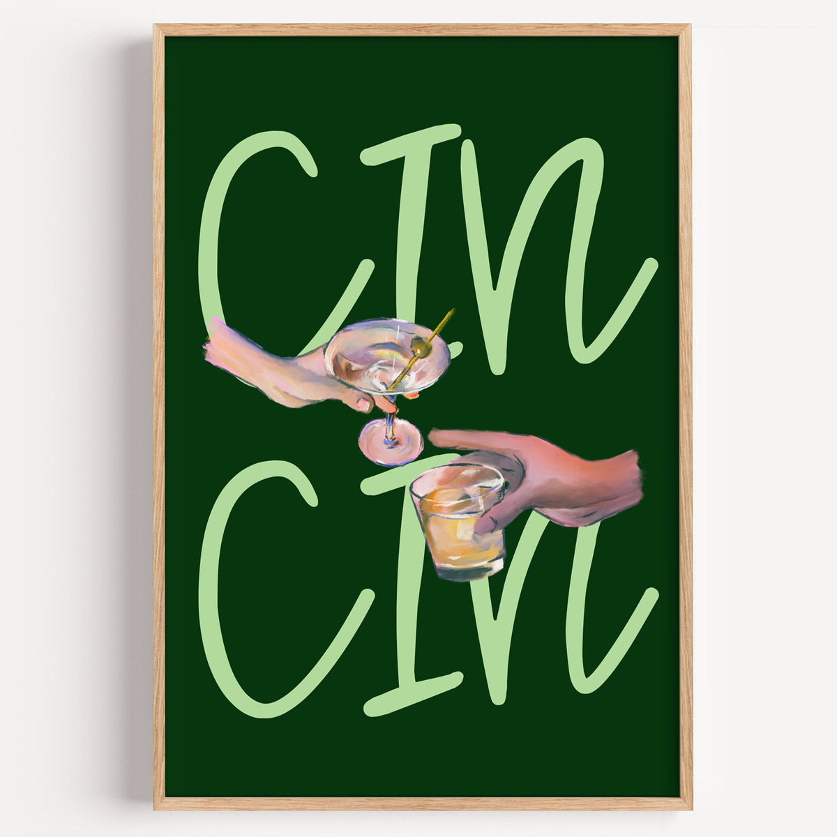 CIN CIN martini and whiskey toast print in a light oak frame on a plain white wall