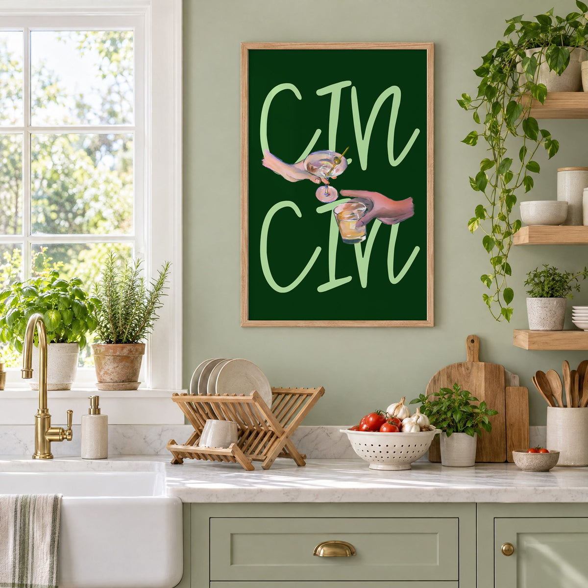 CIN CIN martini and whiskey toast print in an oak frame on a sage green kitchen wall beside a farmhouse sink and herbs