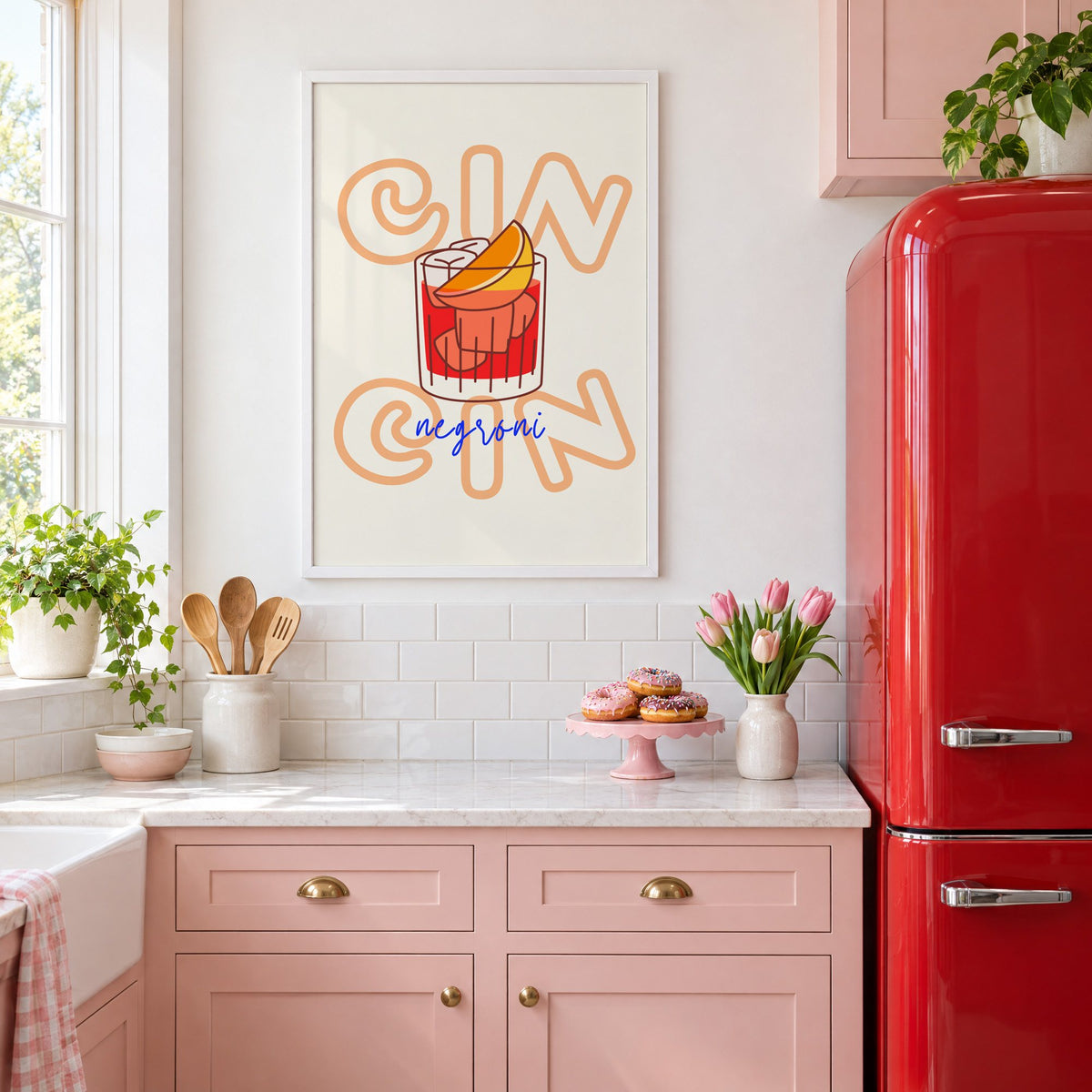 Cin Cin negroni orange slice print in a white frame in a pink kitchen beside a red retro fridge