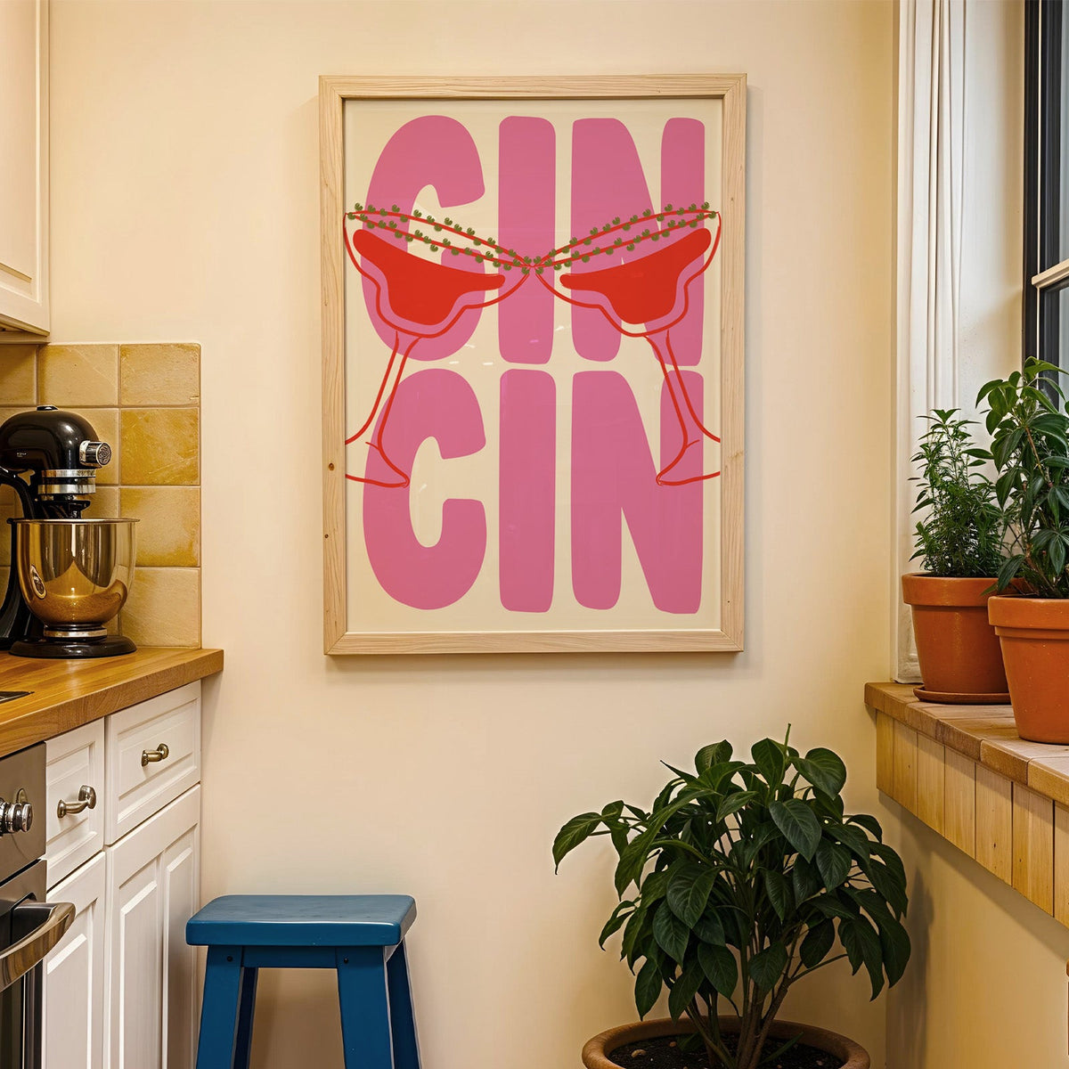 Cin cin pink coupe print in a wood frame on a yellow tiled kitchen wall