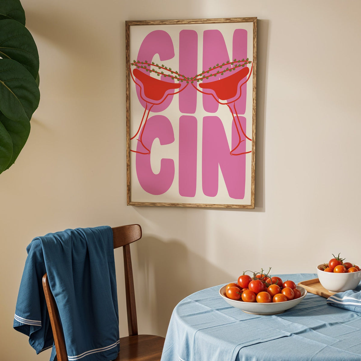 Cin cin pink coupe print in an oak frame above a blue linen table