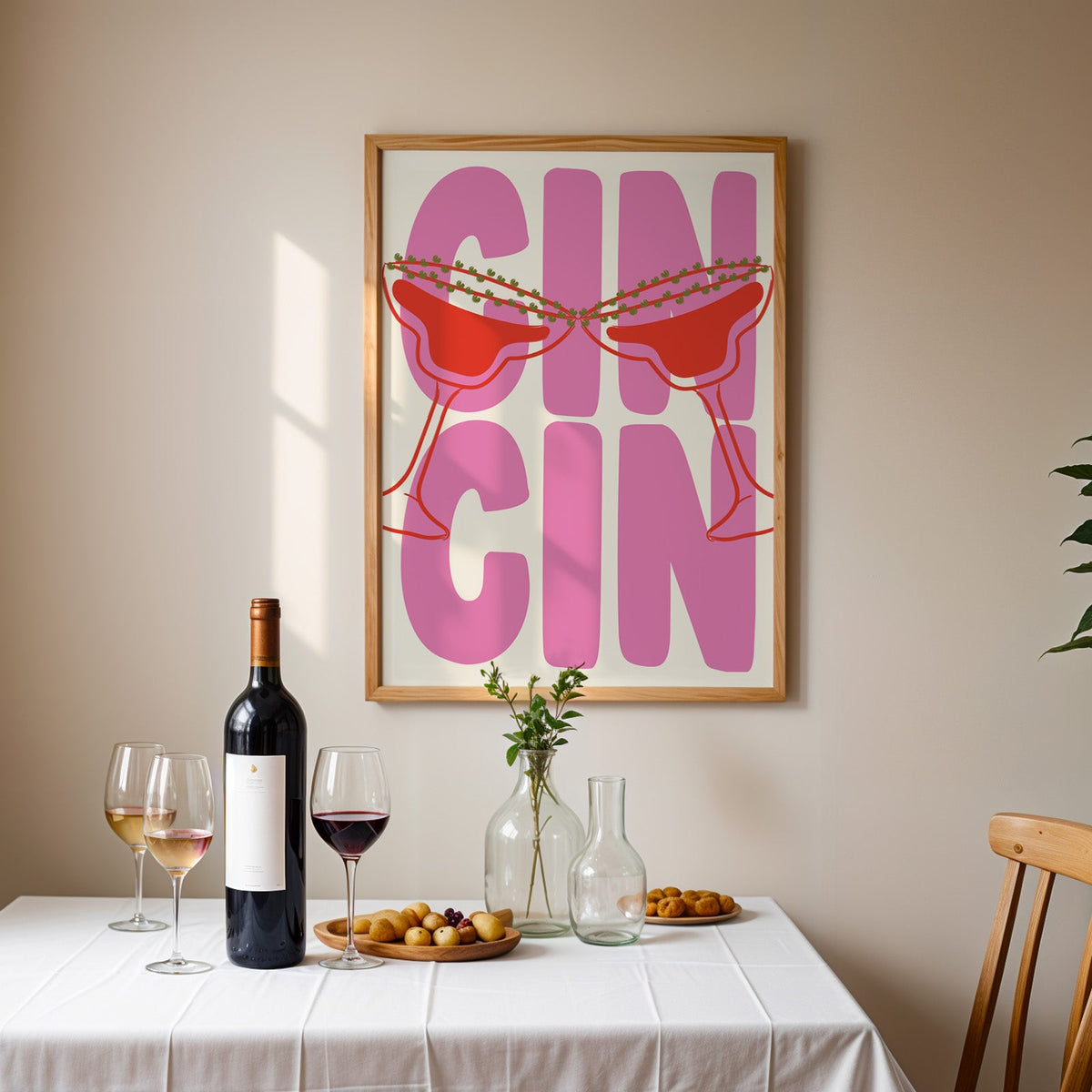 Cin cin pink coupe print in an oak frame above a table laid with wine